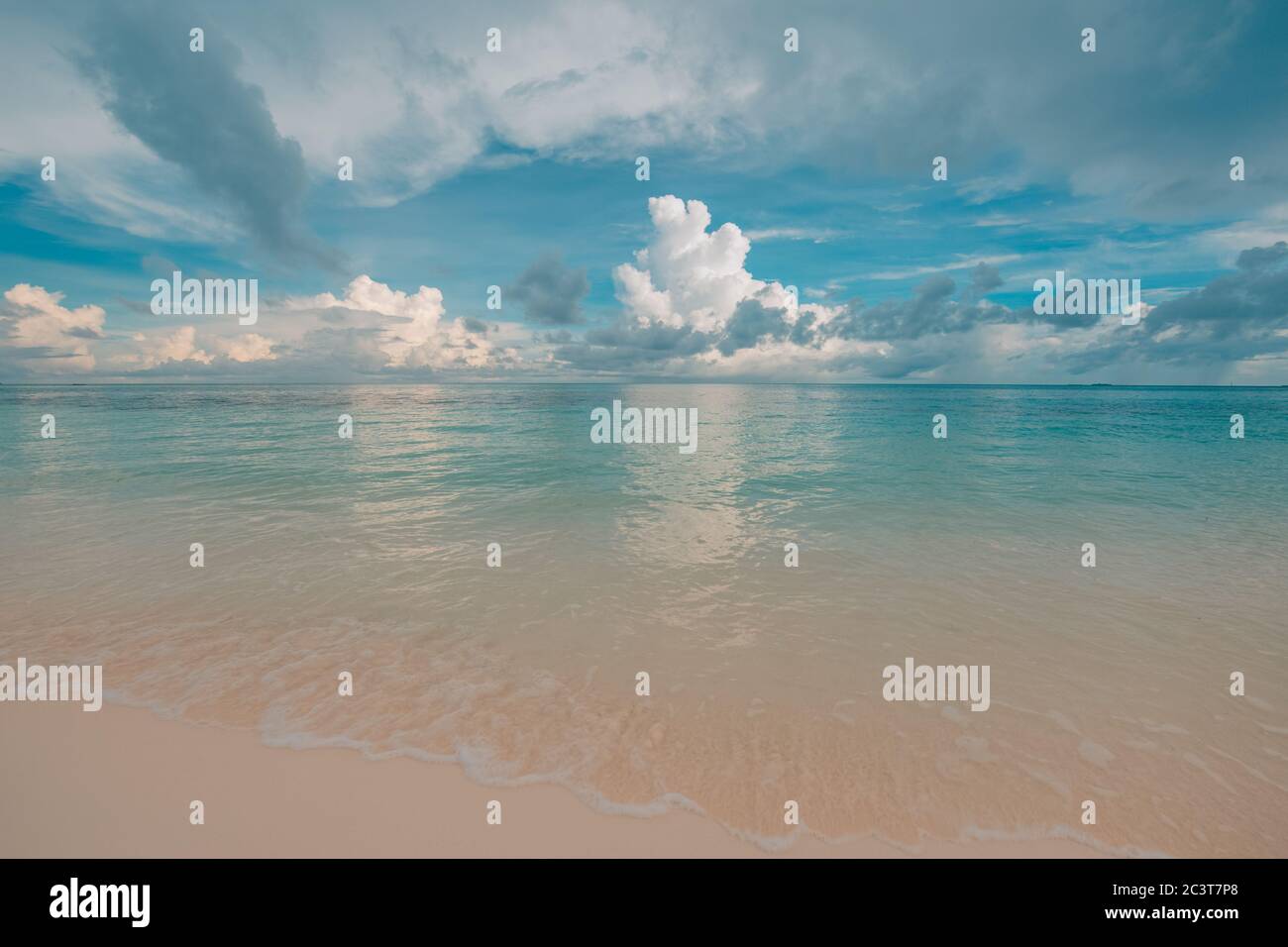 Schöner Strand bei Sonnenuntergang, Ruhe und friedliche Stimmung. Sanfte Orange-Töne über Meer und Horizont. Naturstrand, Küste, Ufer Hintergrund Stockfoto