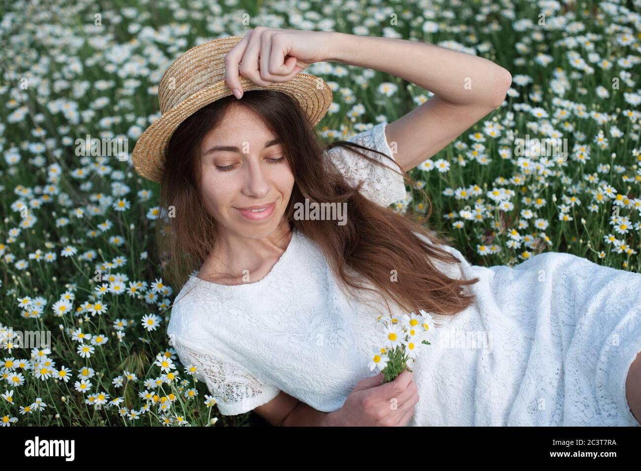 Schöne Frau genießen Kamillenfeld, schöne Frau in der Wiese von Blumen liegen, hübsches Mädchen im Freien entspannen, Spaß haben, glückliche junge Dame Stockfoto