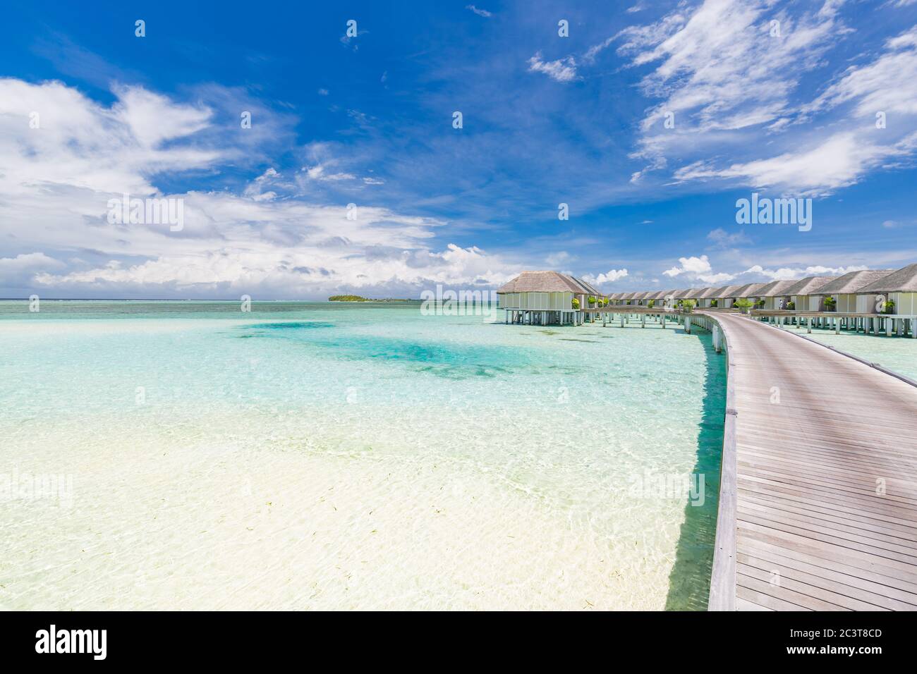 Tropisches Paradies: Blick auf über Wasser Bungalows in einem Resort auf den Malediven, Indischer Ozean. Langer Steg, der unter blauem tropischem Himmel in die Wasservillen führt Stockfoto