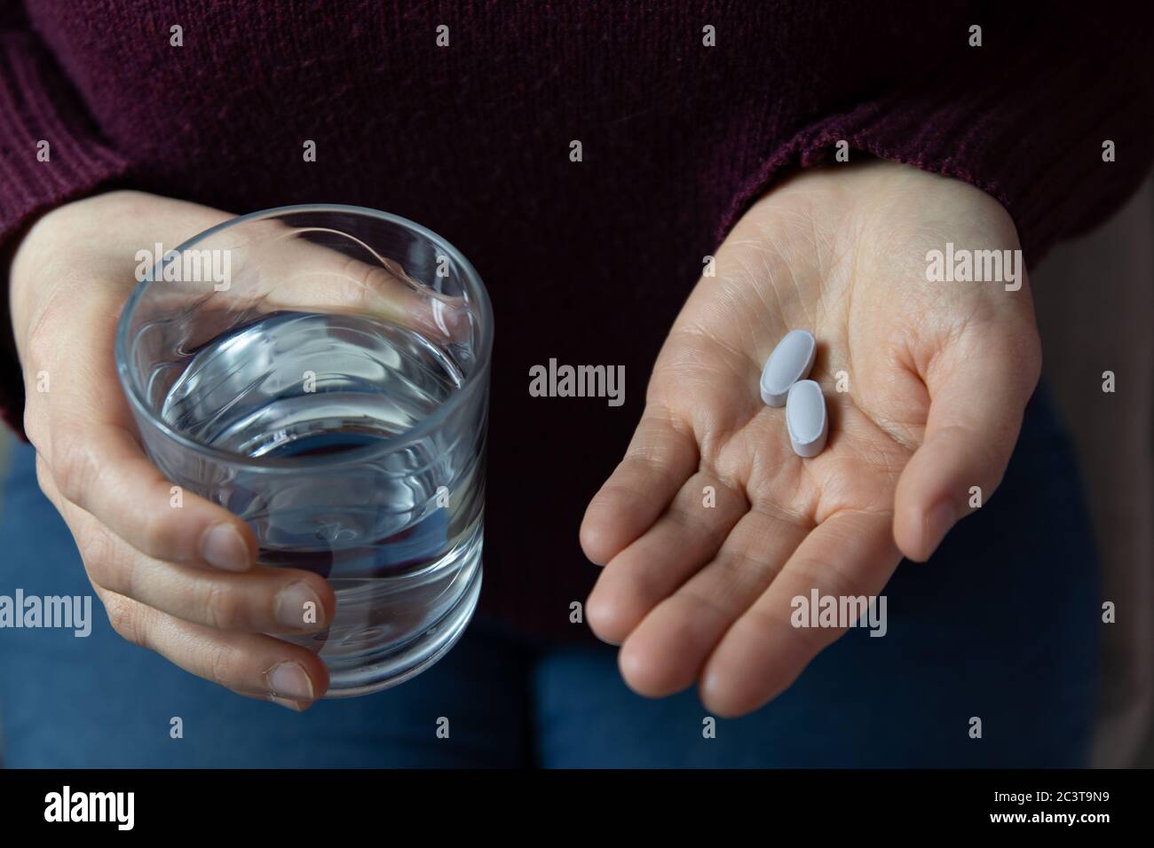 Nahaufnahme der Hände der Frau mit einem Glas Wasser und Pillen zu nehmen. Horizontales Bild. Stockfoto