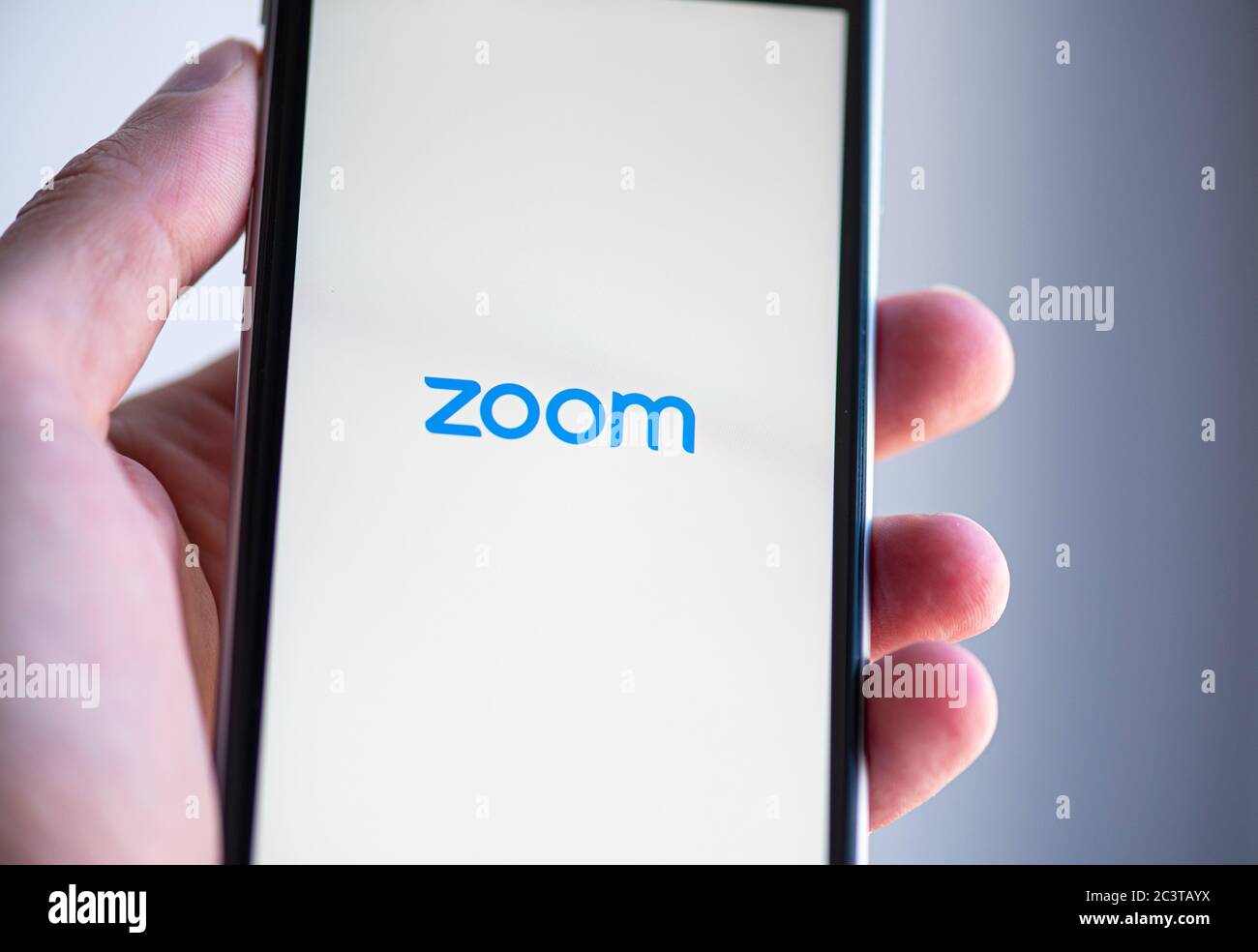 BERLIN - JUN 22: Mann mit Handy mit Logo der ZOOM-Anwendung am 22. Juni in Berlin am Bildschirm. 2020 in Deutschland Stockfoto