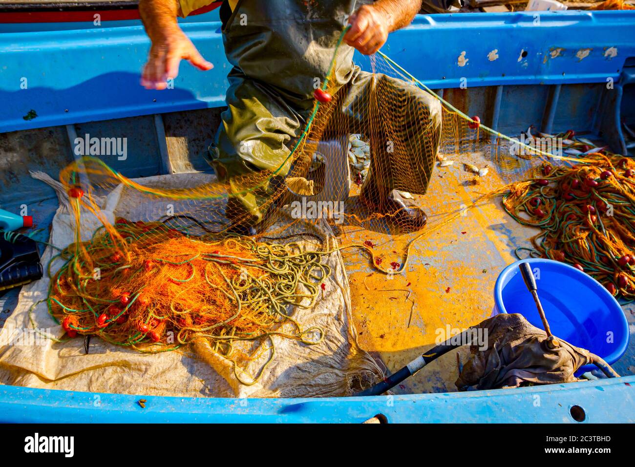 Fisher in Gummihosen und Boot sitzen in seinem Boot und stapeln Angelnetz  für Angeln auf offener See Stockfotografie - Alamy