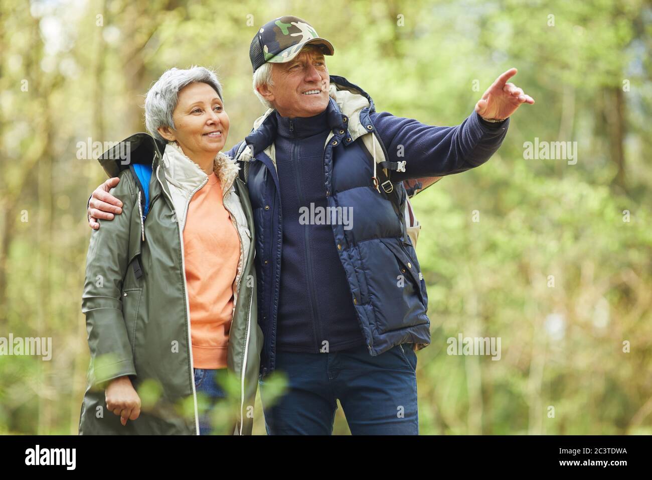 Waist-up-Porträt eines modernen älteren Paares trägt aktiv genießen Wanderung im Wald, konzentrieren sich auf lächelnde Mann zeigt weg, kopieren Raum Stockfoto