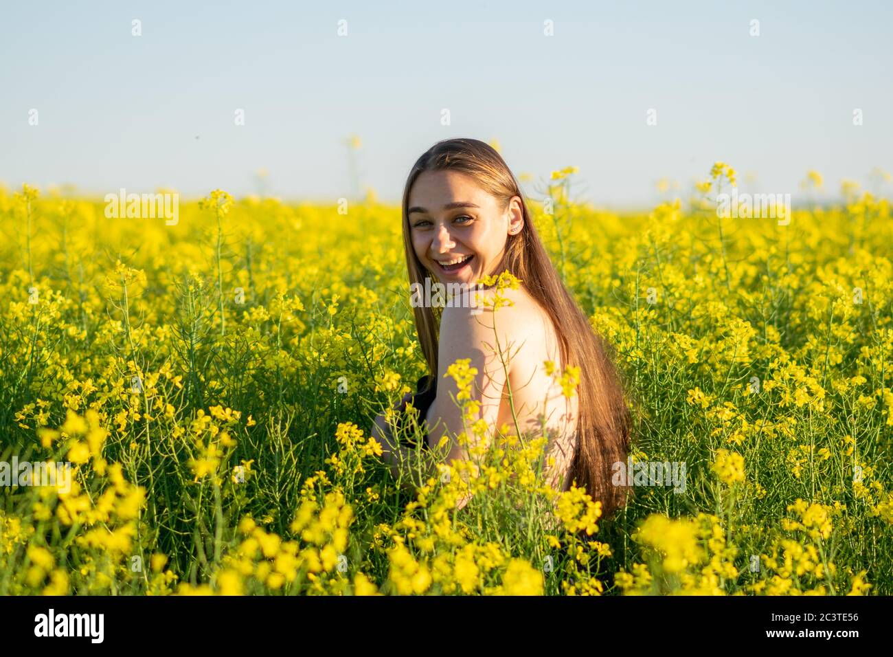 Schönes Mädchen in einem Rapsfeld, mit einer offenen Schulter. Stockfoto