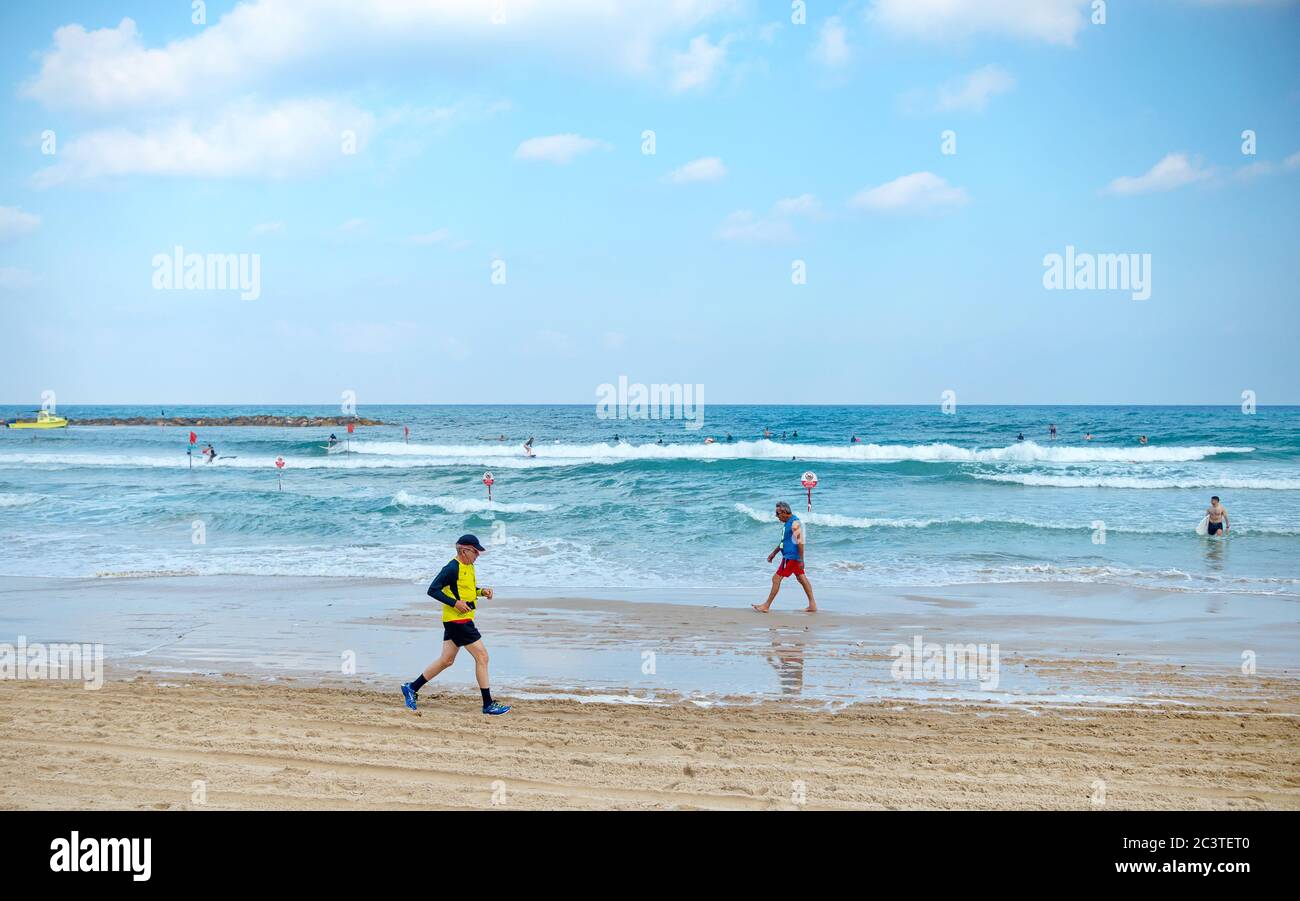 ISRAEL - Strand von Netanya, 29. Juni 2019: Betrieb von Rentnern am Meer. Aktive und glückliche ältere Männer, die am Strand herumlaufen Stockfoto