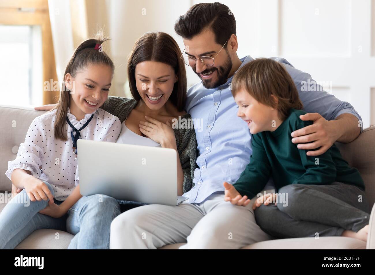 Glückliche Familie, die Spaß mit dem Laptop zu Hause zusammen Stockfoto