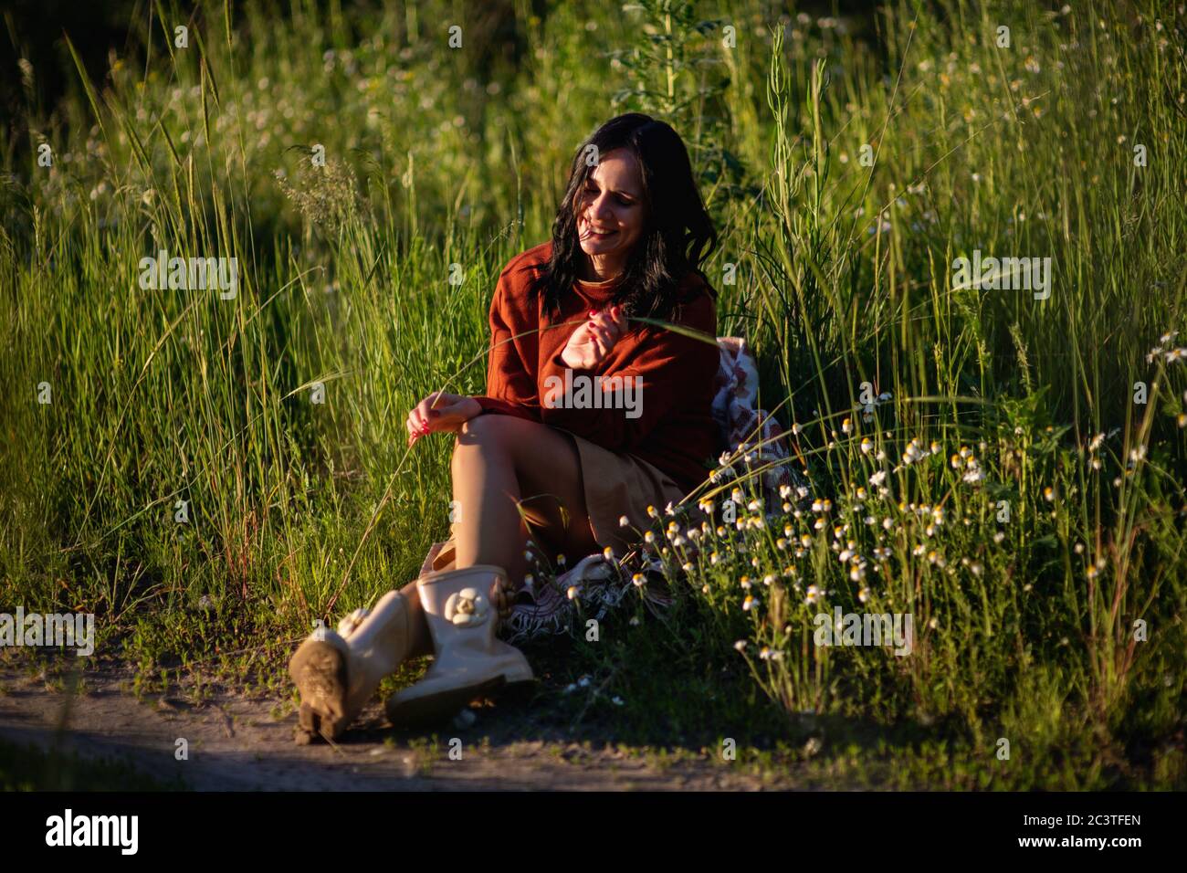 Junge schöne lächelnde Frau auf Gras im Freien sitzen. Stockfoto