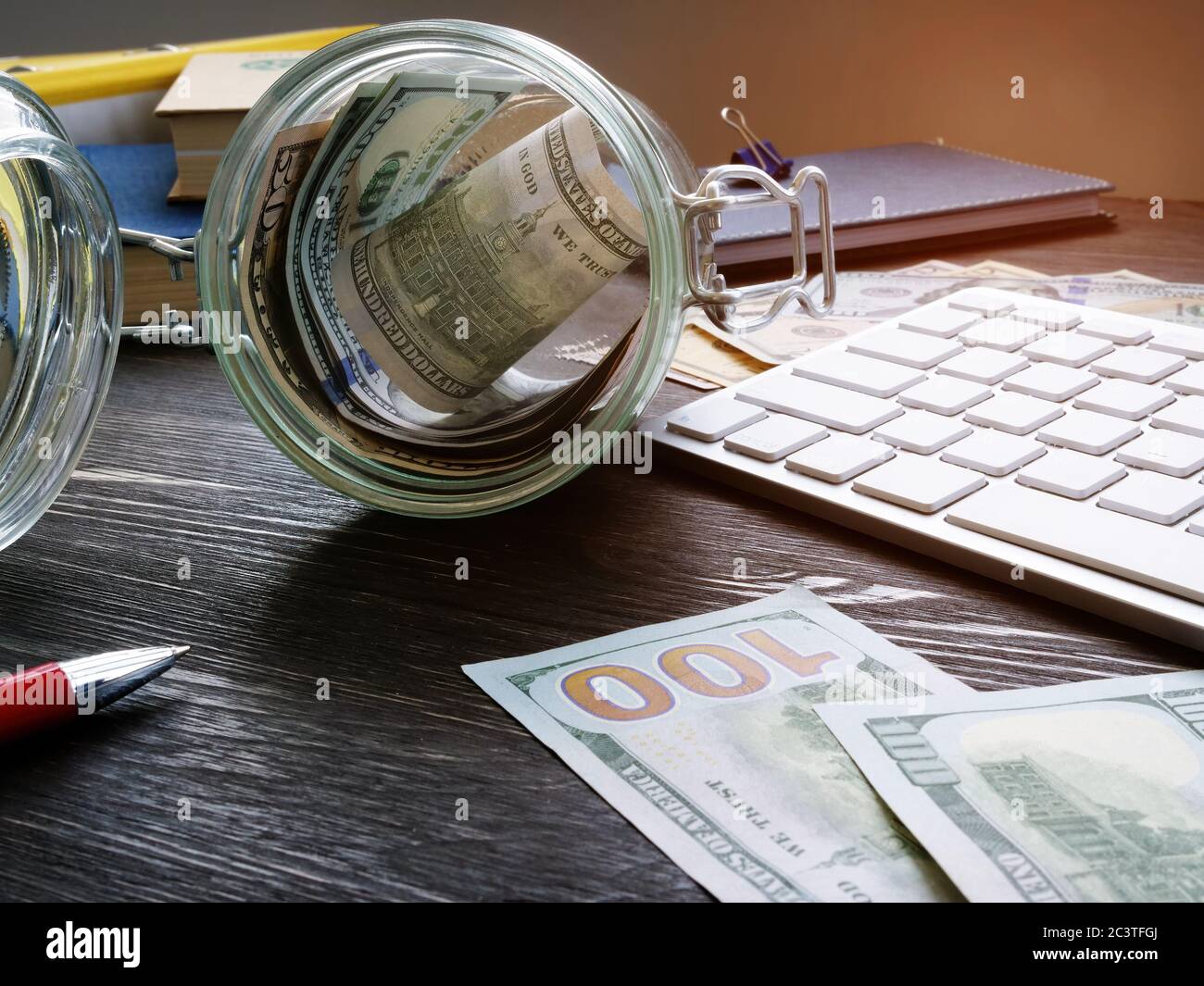 Glas mit Geld auf dem Schreibtisch. Sparkonzept und Konzept der persönlichen Finanzen. Stockfoto