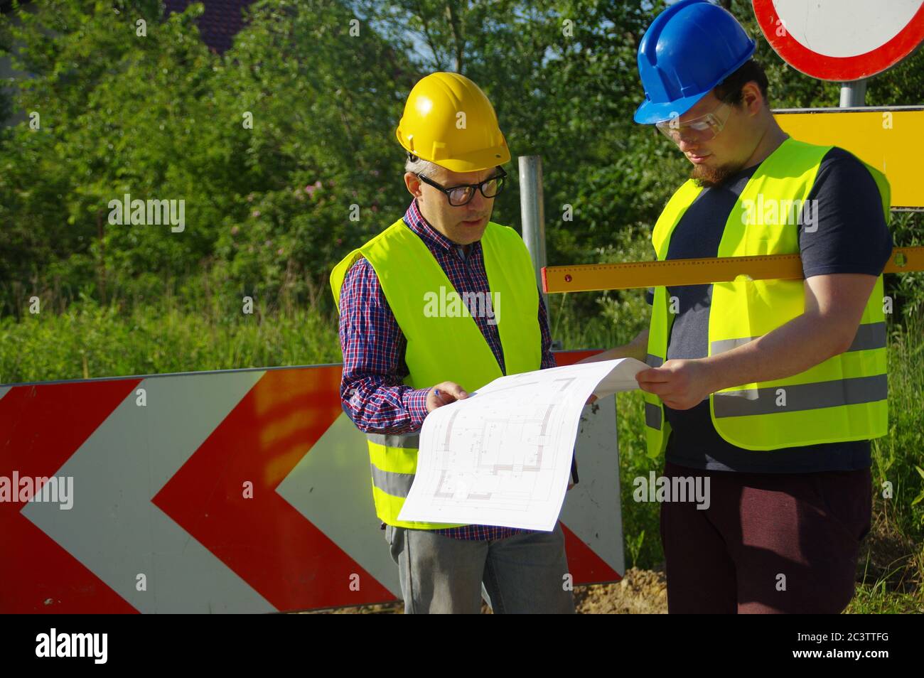 Teamwork Planung und Umsetzung. Ingenieur und Arbeiter in Helmen auf einer Baustelle. Eine geschäftliche Metapher für Konsens, Erfolg und Erfolg Stockfoto