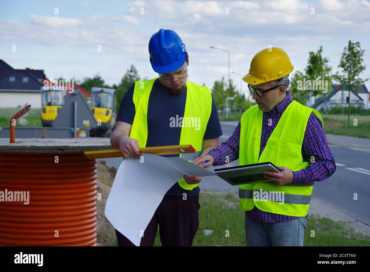 Teamwork Planung und Umsetzung. Ingenieur und Arbeiter in Helmen auf einer Baustelle. Eine geschäftliche Metapher für Konsens, Erfolg und Erfolg Stockfoto