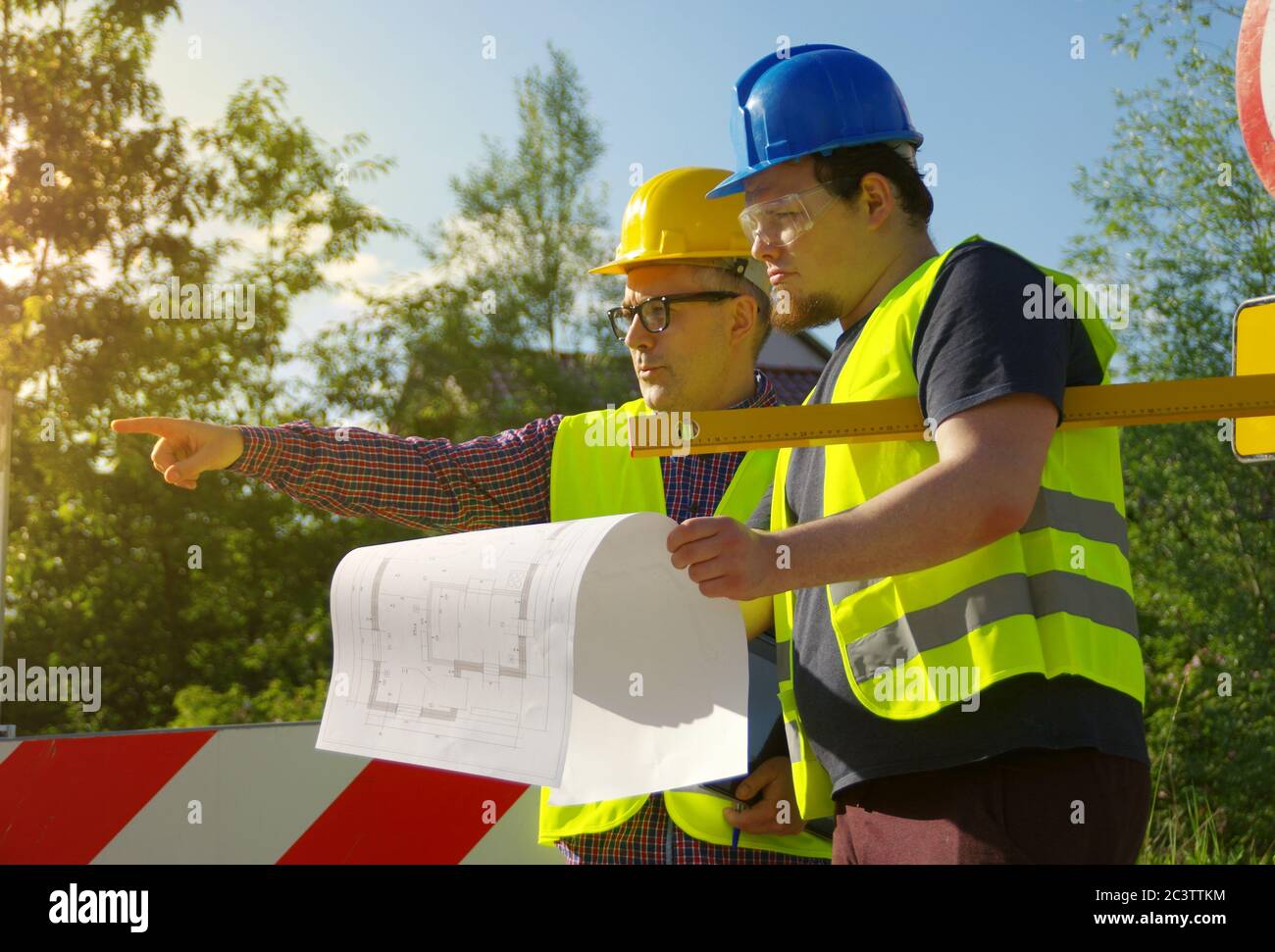 Ingenieur und Arbeiter in Helmen auf einer Baustelle. Eine geschäftliche Metapher für Konsens, Erfolg und gemeinsame Lösungen. Teamwork-Planung Stockfoto
