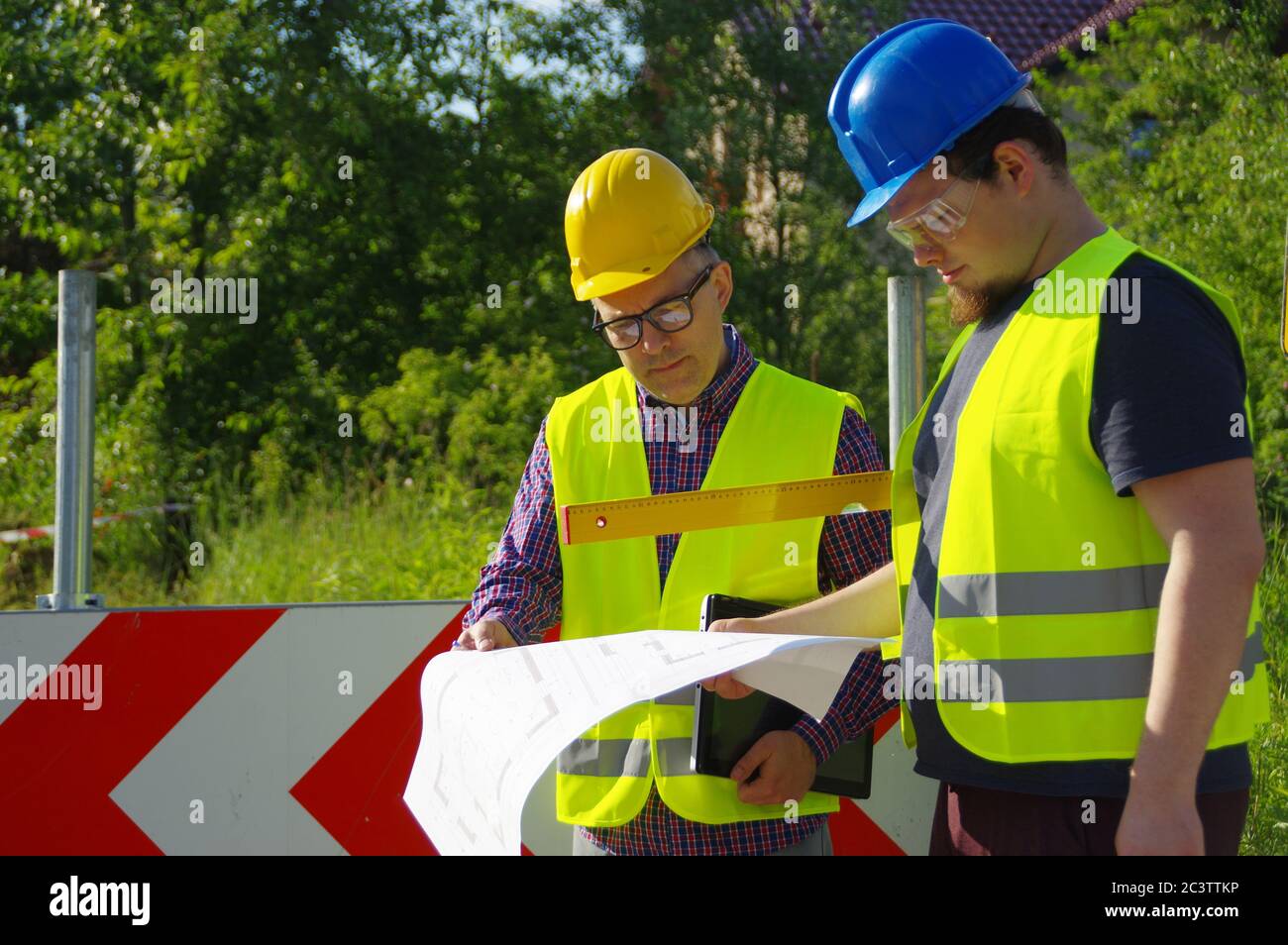 Ingenieur und Arbeiter in Helmen auf einer Baustelle. Eine geschäftliche Metapher für Konsens, Erfolg und gemeinsame Lösungen. Teamwork-Planung Stockfoto