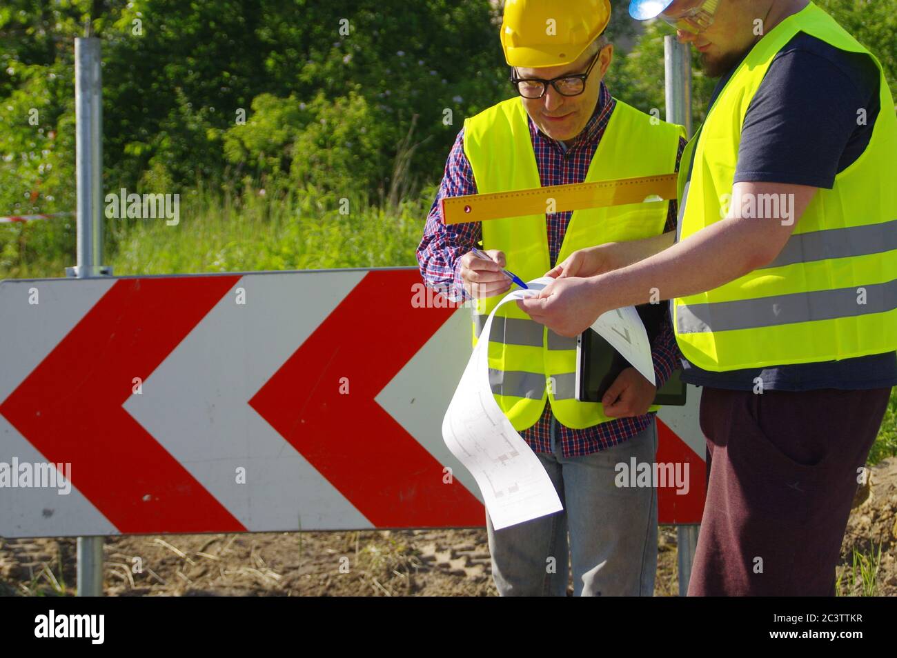 Teamwork Planung und Umsetzung. Ingenieur und Arbeiter in Helmen auf einer Baustelle. Eine geschäftliche Metapher für Konsens, Erfolg und Erfolg Stockfoto