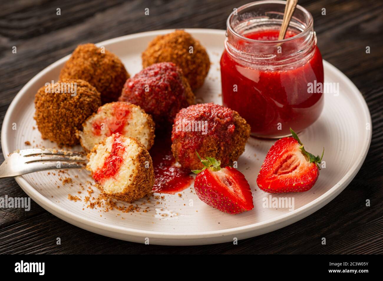 Hausgemachte Quark-Bälle, ungarische süße Nachspeise mit Erdbeermousse serviert. Stockfoto