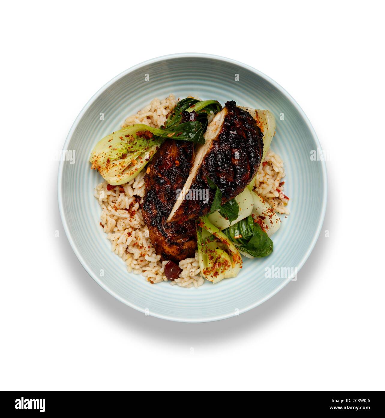 Eine köstliche Schüssel mit Jerk Huhn, Reis und Gemüse, in einer hellblauen Schüssel isoliert auf weißem Hintergrund Stockfoto