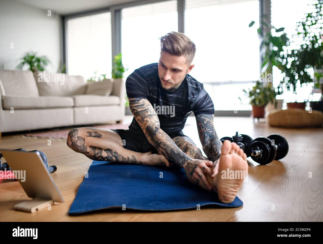 Vorderansicht Porträt des Mannes mit Tablet, der zuhause Workout macht. Stockfoto