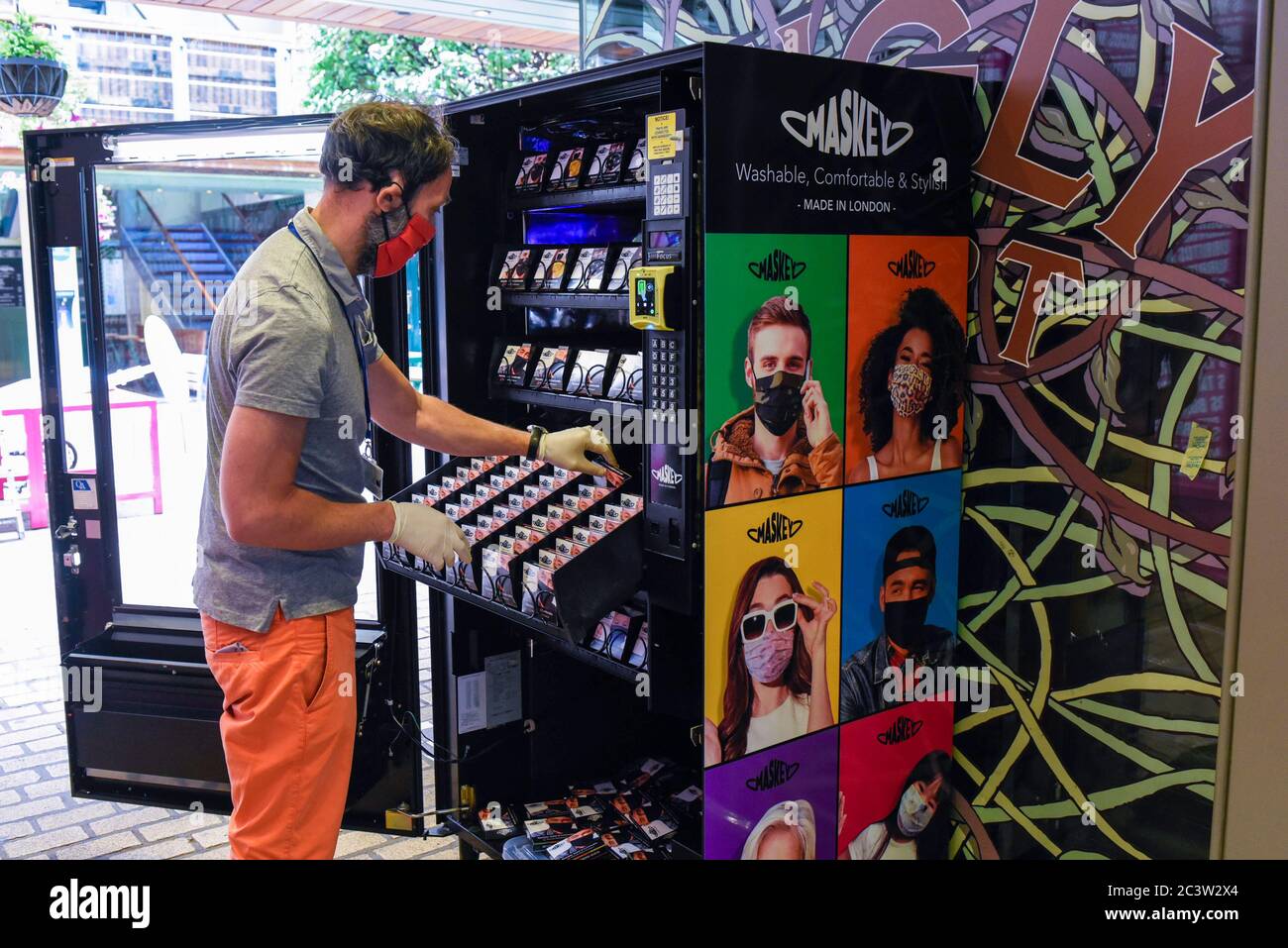 London, Großbritannien. 22. Juni 2020. Ein Mitarbeiter lädt einen Automaten in der Carnaby Street, der der Öffentlichkeit Gesichtsmasken des Londoner Unternehmens Maskey verkauft. Das neu gegründete Unternehmen wurde von Unternehmer Adam Freeman gegründet, um der Nachfrage nach erschwinglichen Gesichtsmasken aus Großbritannien während der laufenden Coronavirus-Pandemie gerecht zu werden. Es installiert die ersten modischen Verkaufsautomaten für Gesichtsmasken in Großbritannien an Standorten in London, die weiter ausgebaut werden sollen. 10% des Gewinns aus jedem Facemask-Verkauf wird an eine Wohltätigkeitsorganisation gespendet, die das NHS unterstützt. Kredit: Stephen Chung / Alamy Live Nachrichten Stockfoto