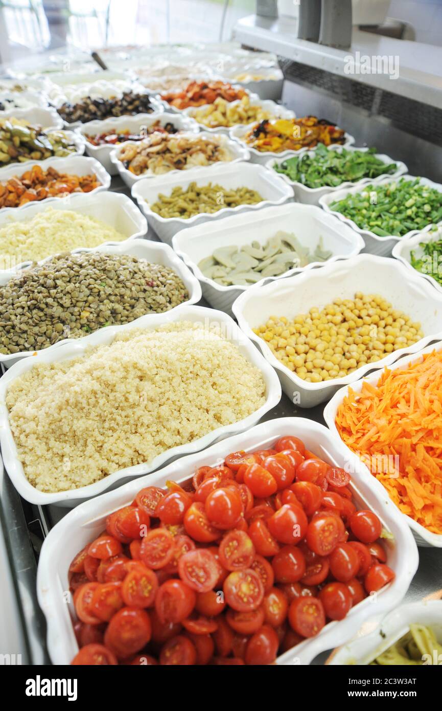 Schneiden Sie die Zutaten für den Salat an einer Salatbar Stockfoto