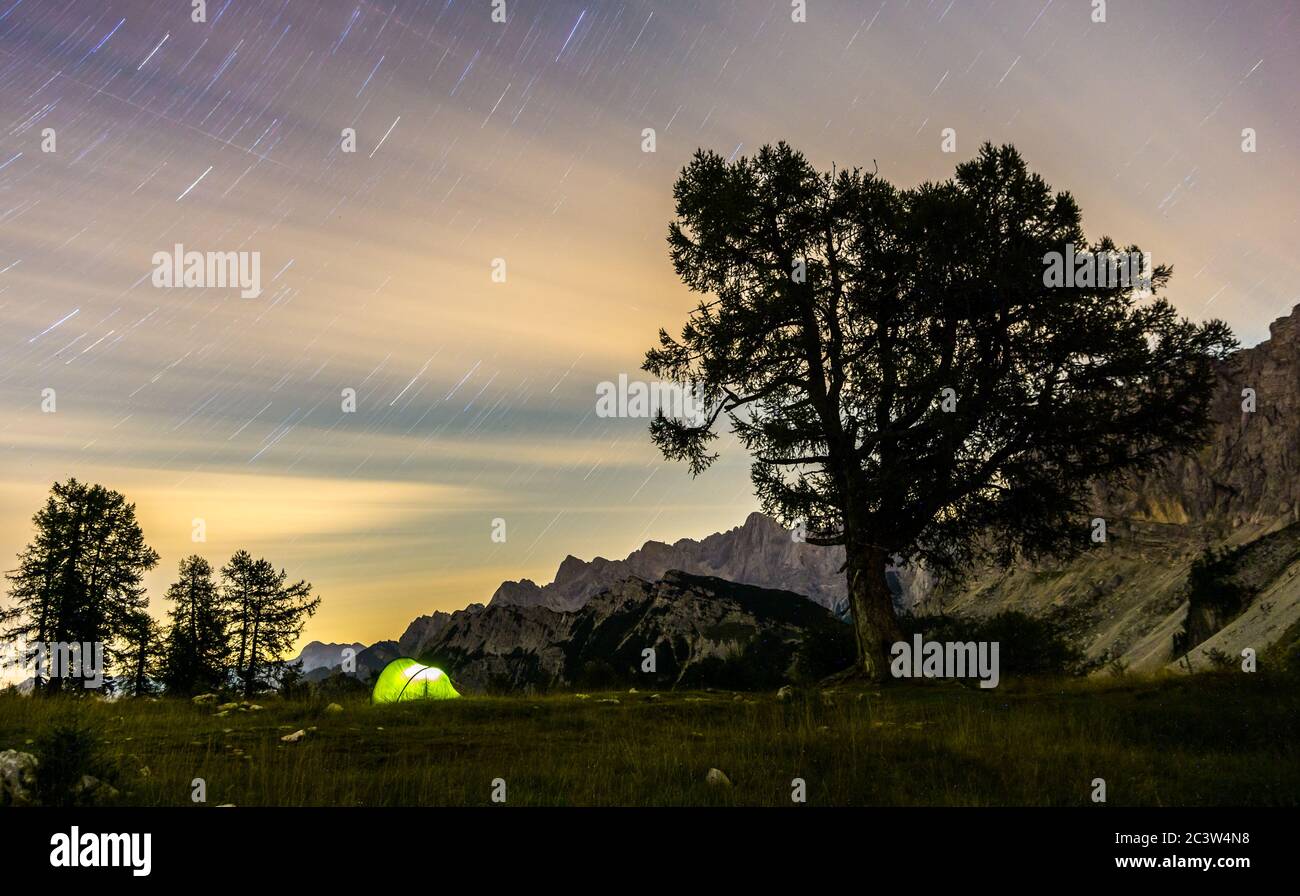Ein Zelt leuchtet unter einem Stern Trails Nachthimmel in der Dämmerung Stunde. Julische Alpen, Triglav Nationalpark, Slowenien, Slemenova Gebirge, Sleme. Stockfoto