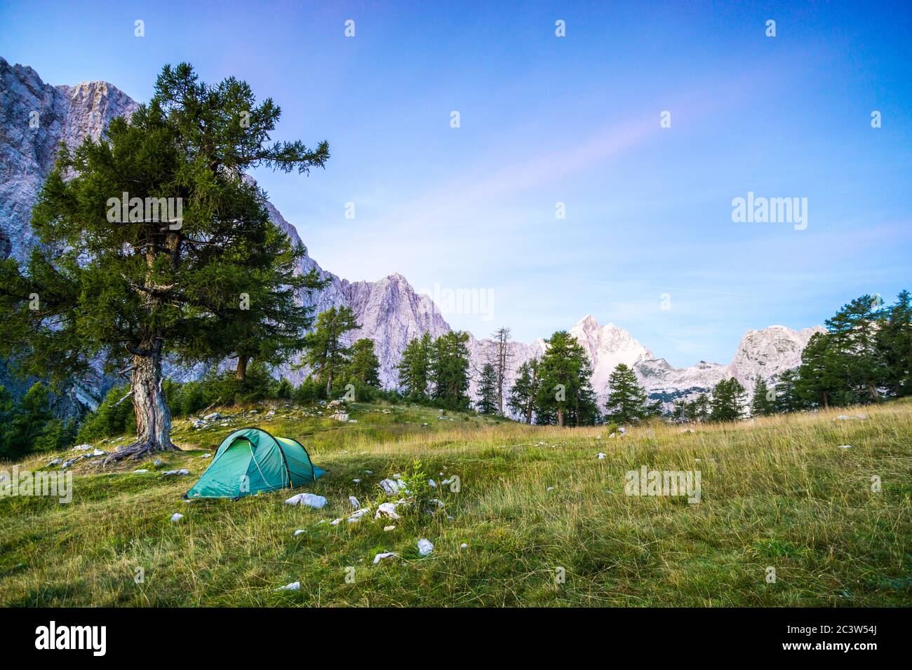 Ein Zelt leuchtet unter einem Mondnachthimmel zur Dämmerung. Die Julischen Alpen, Nationalpark Triglav, Slowenien. Blick vom Berg Slemenova, Sleme zum Berg Stockfoto