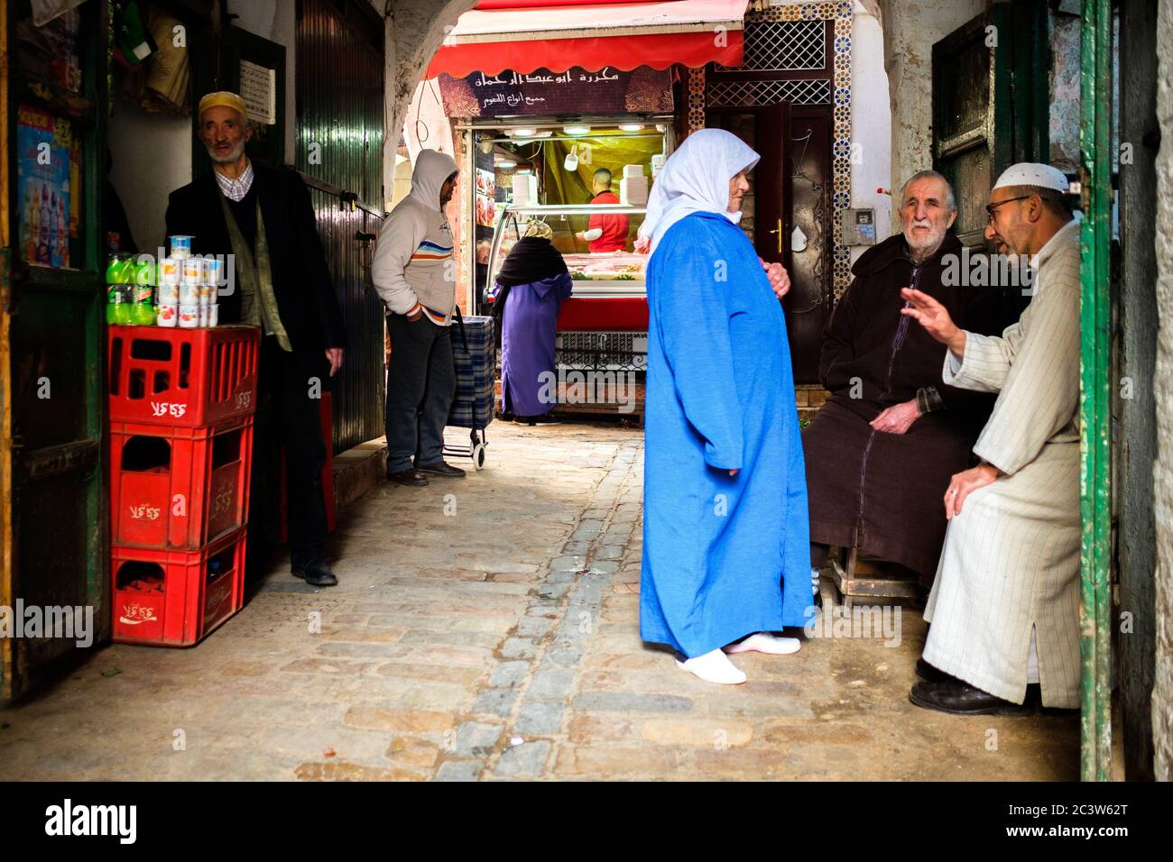 Marokko, Tetouan: Atmosphäre in einer Gasse der Altstadt. Eine ältere Frau, die mit alten Männern spricht. Die Medina von Tetouan ist als UNESCO World H registriert Stockfoto