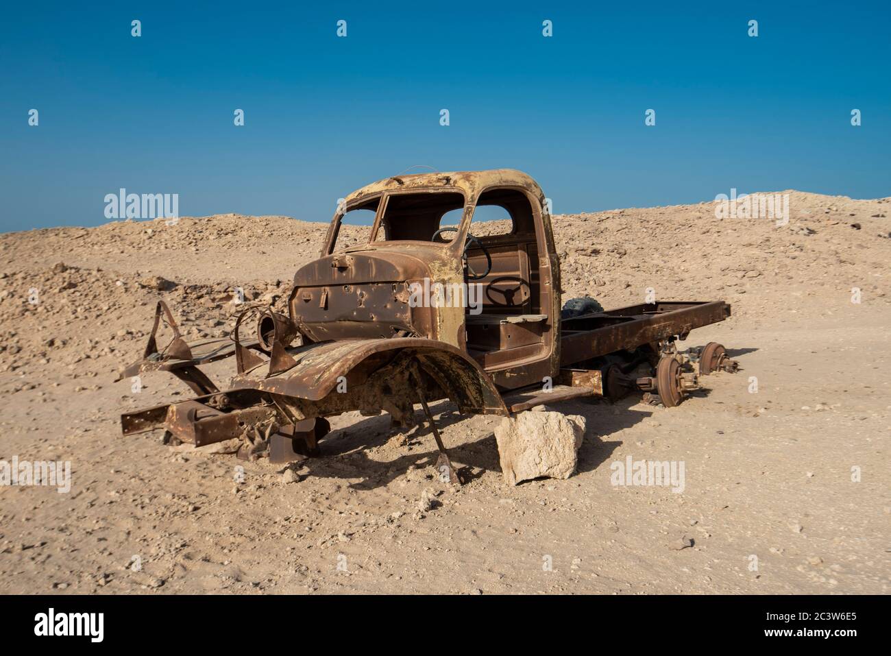 Überreste eines verrosteten alten verlassenen LKW, der in der Wüste dem Verfall überlassen wurde Stockfoto