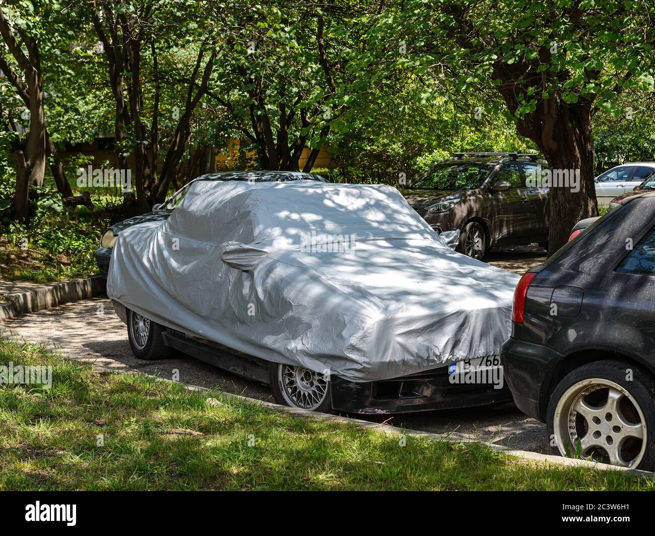 Varna, Bulgarien, 18. Juni 2020. Silberne wetterfeste Abdeckung auf einem stationären Auto im Freien geparkt. Moderne Autoabdeckungen schützen vor Hitze, Regen, Staub und UV. Stockfoto