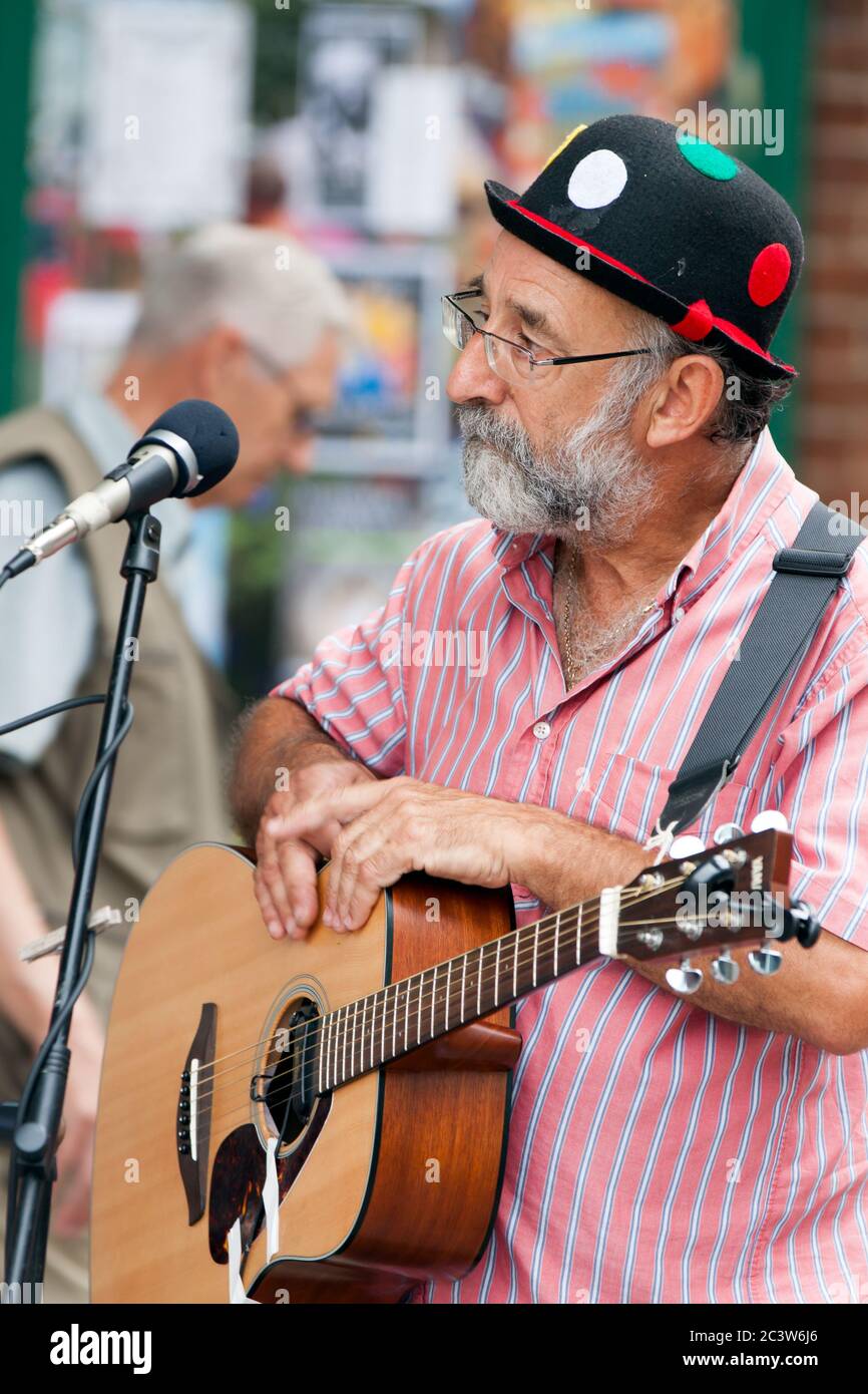 Gitarrist mit der Band Accoustic Rooster unterhält Leute, die Country-Musik und Volkslieder an einem Wochenendmorgen auf dem Bucky Doo Square in Bridport spielen. Stockfoto