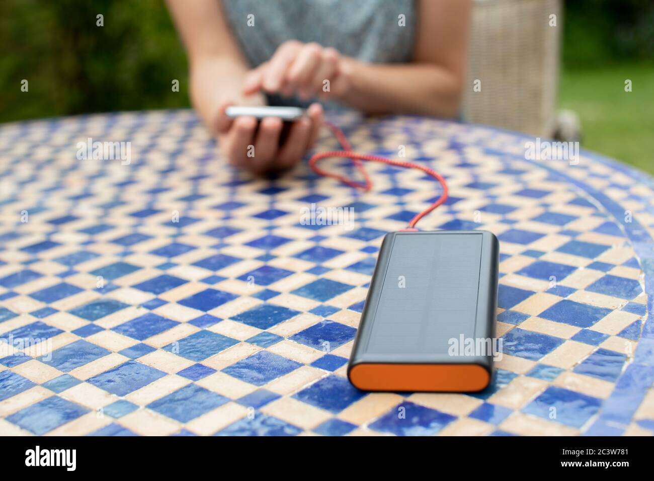 Frau Lädt Handy Im Freien Zu Hause Mit Tragbaren Solar Power Bank Stockfoto