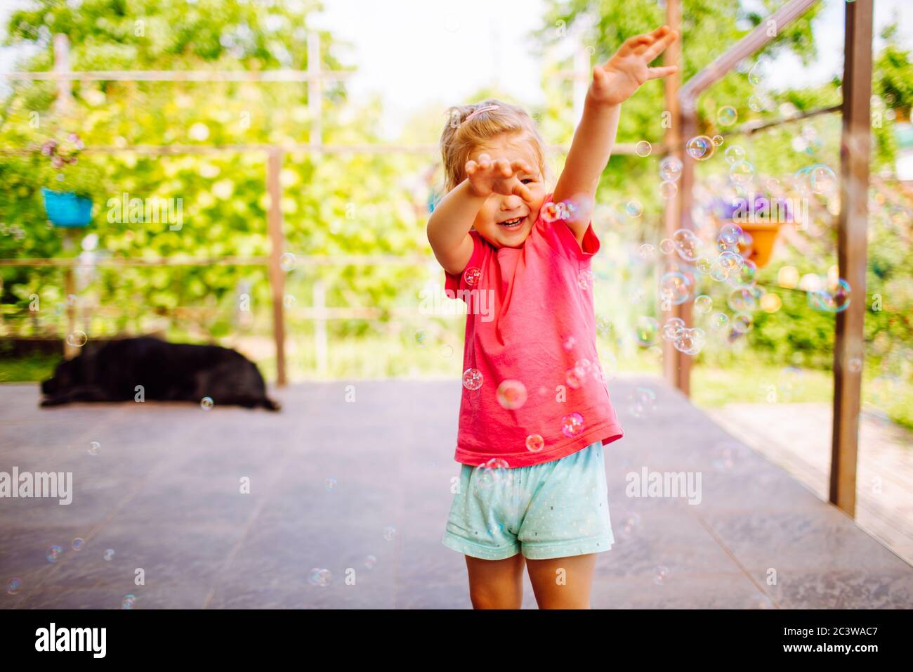Kleine blonde Mädchen fangen eine Seife Blasen. Glückliche Kindheit, Sommerurlaub Konzept Stockfoto