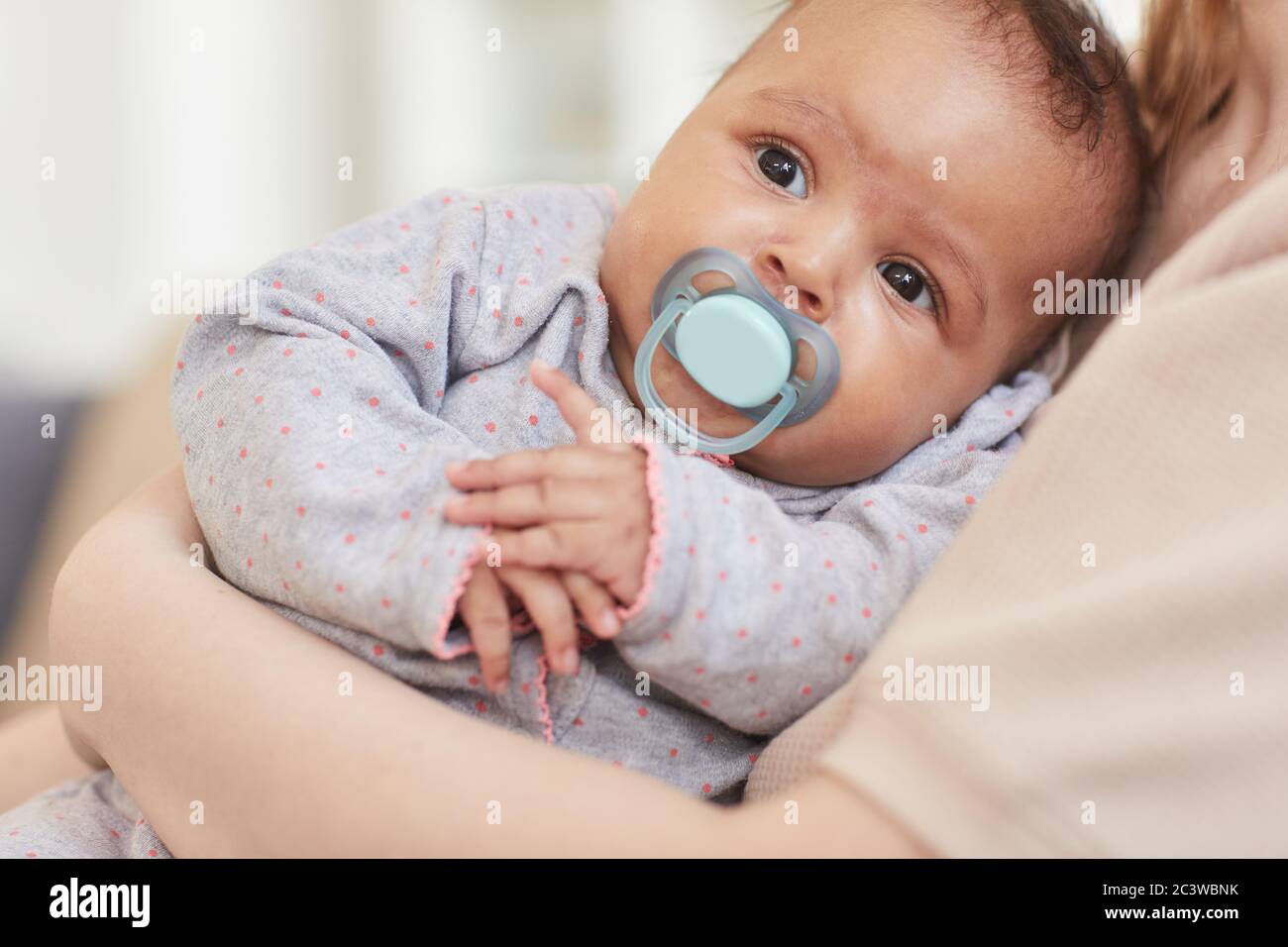 Nahaufnahme Porträt von niedlichen Mixed-Race Baby saugen auf Schnuller während in Mütter Arme, kopieren Raum Stockfoto