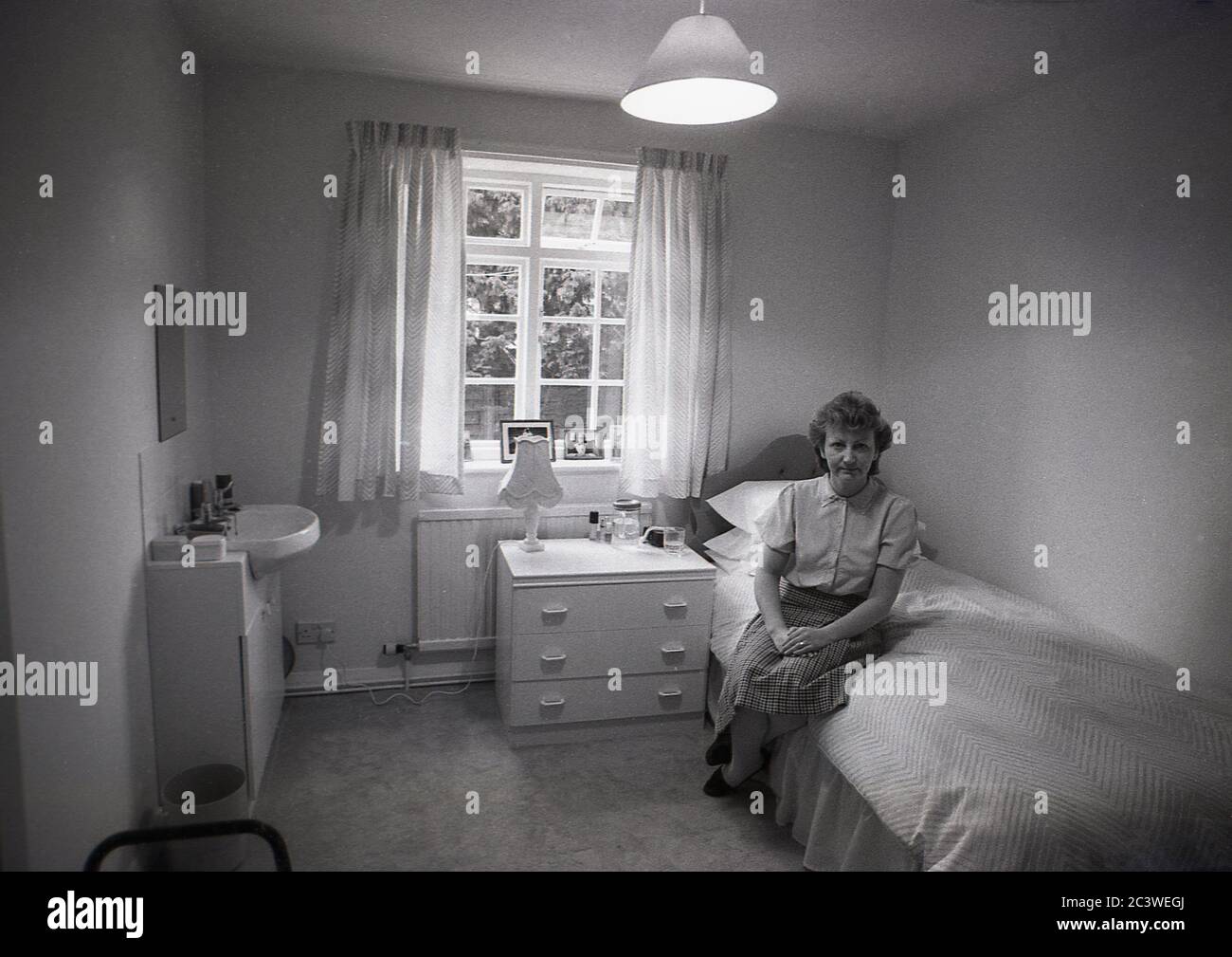 Lady Manager sitzt in einem Schlafzimmer eines Residenten in einem Pflege-oder Pflegeheim, zeigt die Unterkunft für ihre Bewohner, England, ca. 1980er Jahre. Stockfoto