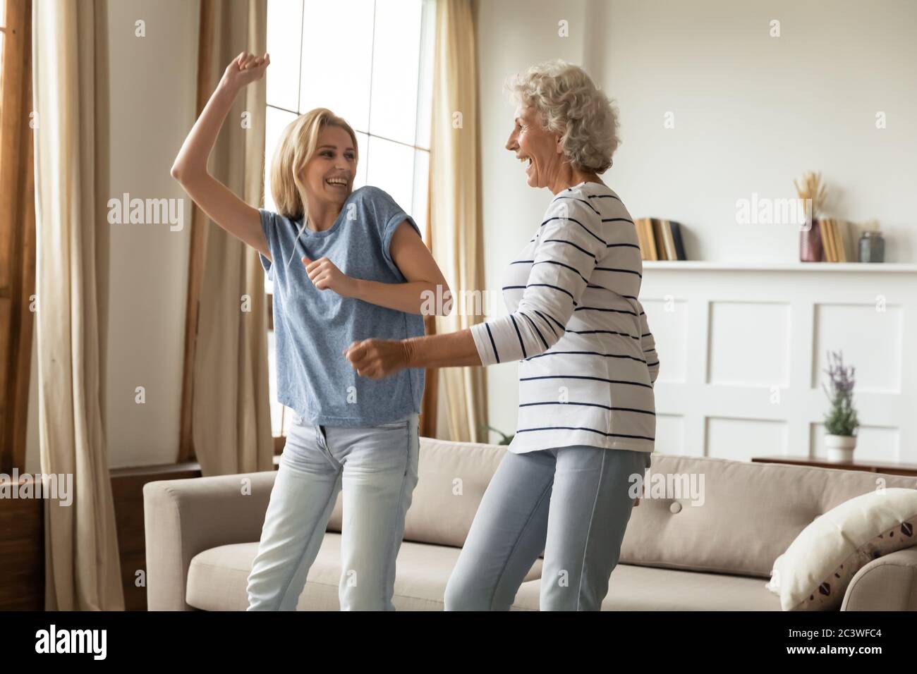 Erwachsene Enkelin und ältere Großmutter tanzen zu Hause fühlt sich glücklich Stockfoto