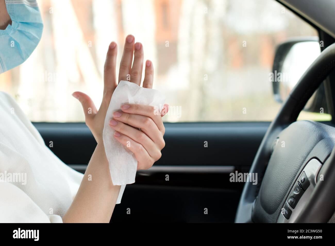 Weibliche Hände werden mit einem antiseptischen Tuch in einem behandelt Auto Stockfoto