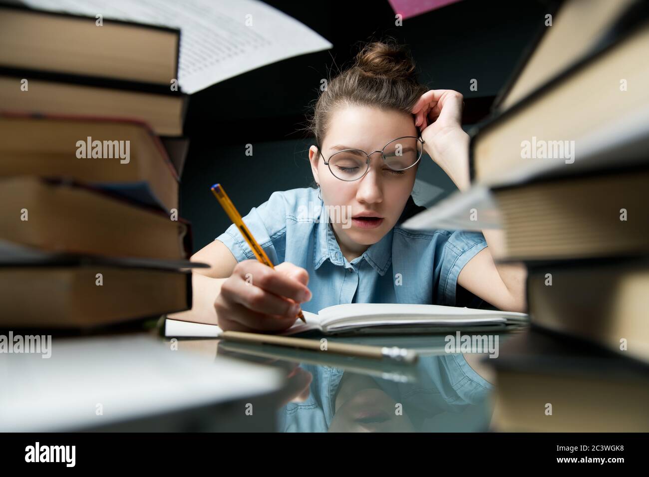 Vorbereitung auf Prüfungen. Ein junges Mädchen mit Brille schläft vor Müdigkeit ein Stockfoto