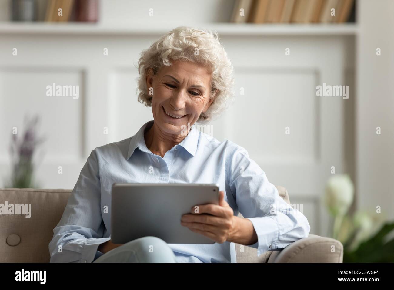 Ältere Frau mit Tablet-Surfen im Web chatten mit Freunden mit Messenger Stockfoto