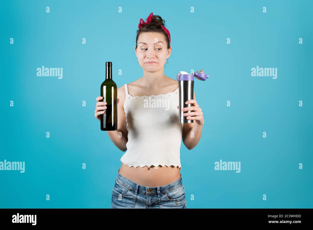 Junge Frau, die eine Weinflasche und eine Thermoskanne hält, sieht flyly aus Stockfoto