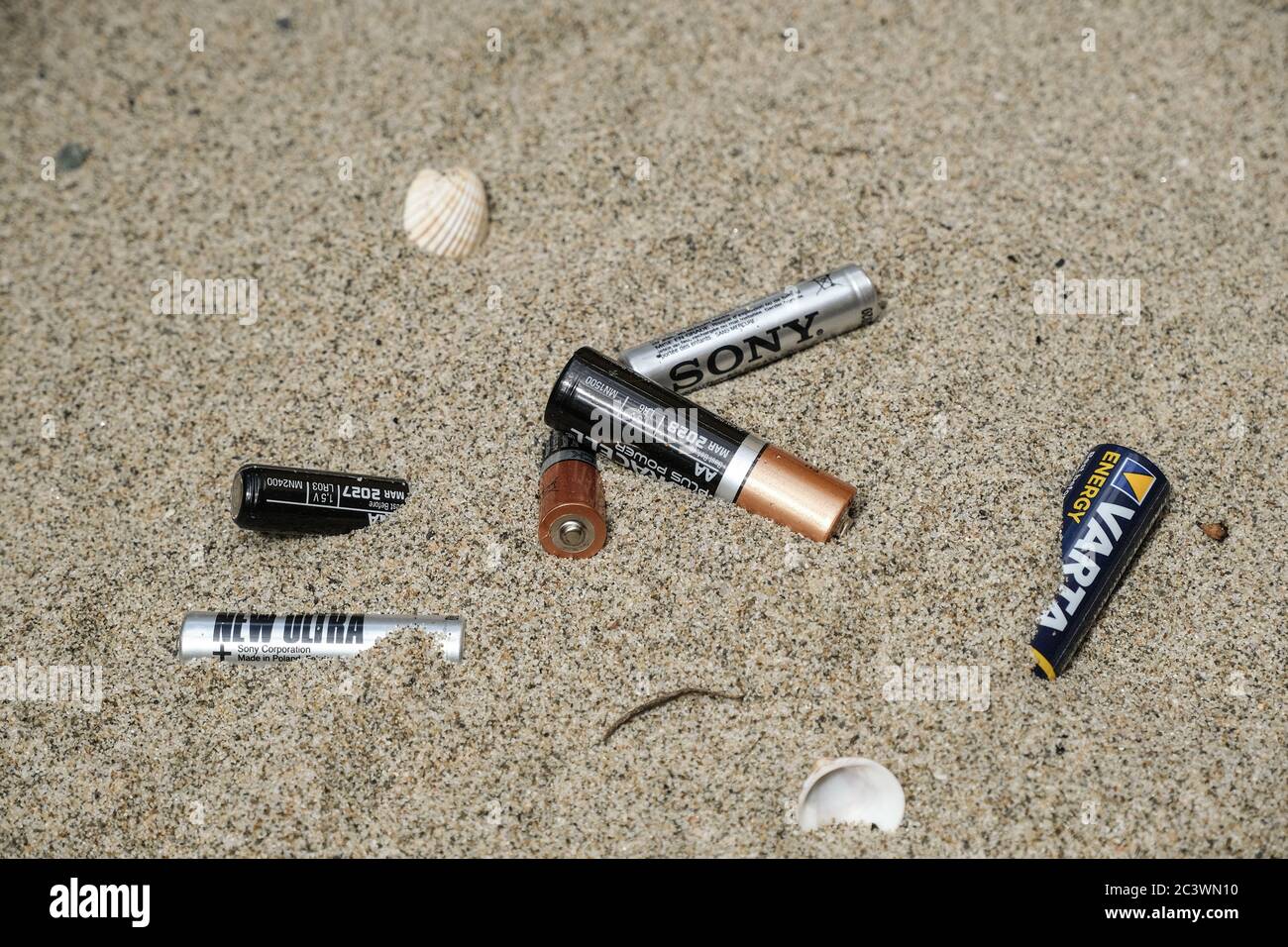 Elektronische weggeworfene Batterieabfälle auf sandigen Meeresküsten Ökosystem, Meeresverschmutzung Krankheit Stockfoto