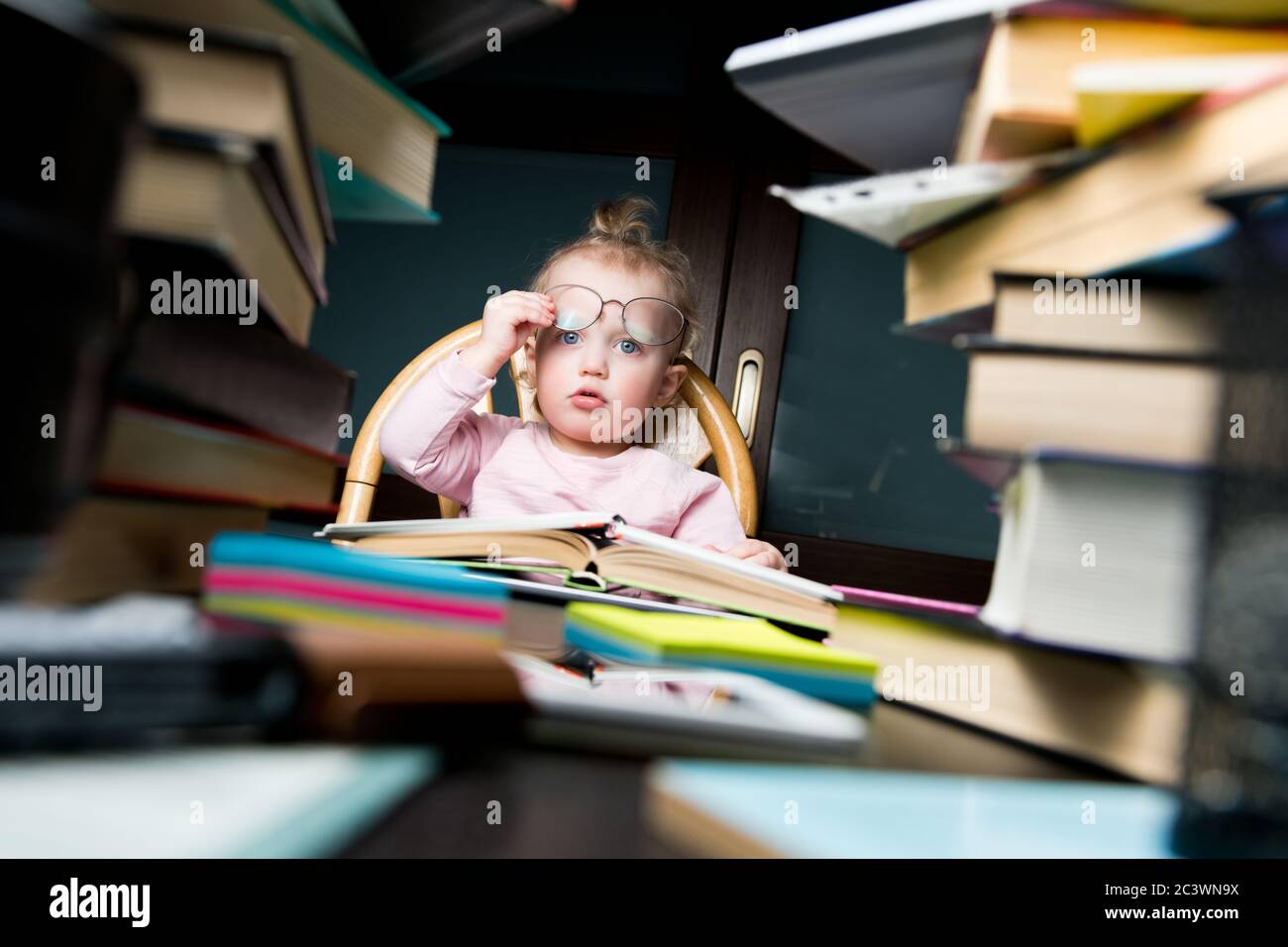 Schwierigkeiten der frühen Bildung. Das kleine Mädchen sitzt am späten Abend in Büchern Stockfoto