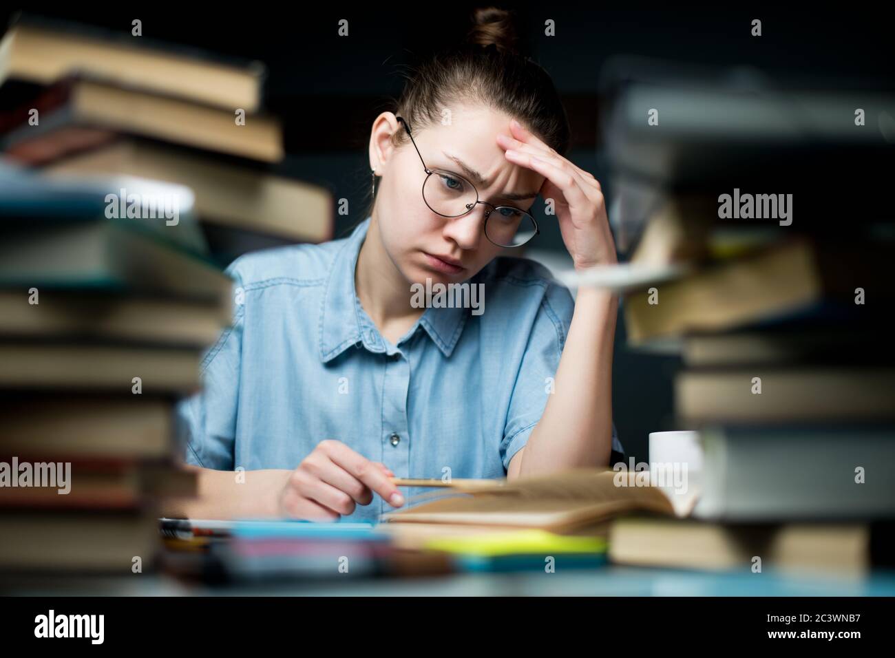 Der Student sieht sich die Lernmaterialien erträgt an, studiert aber immer noch spät Stockfoto