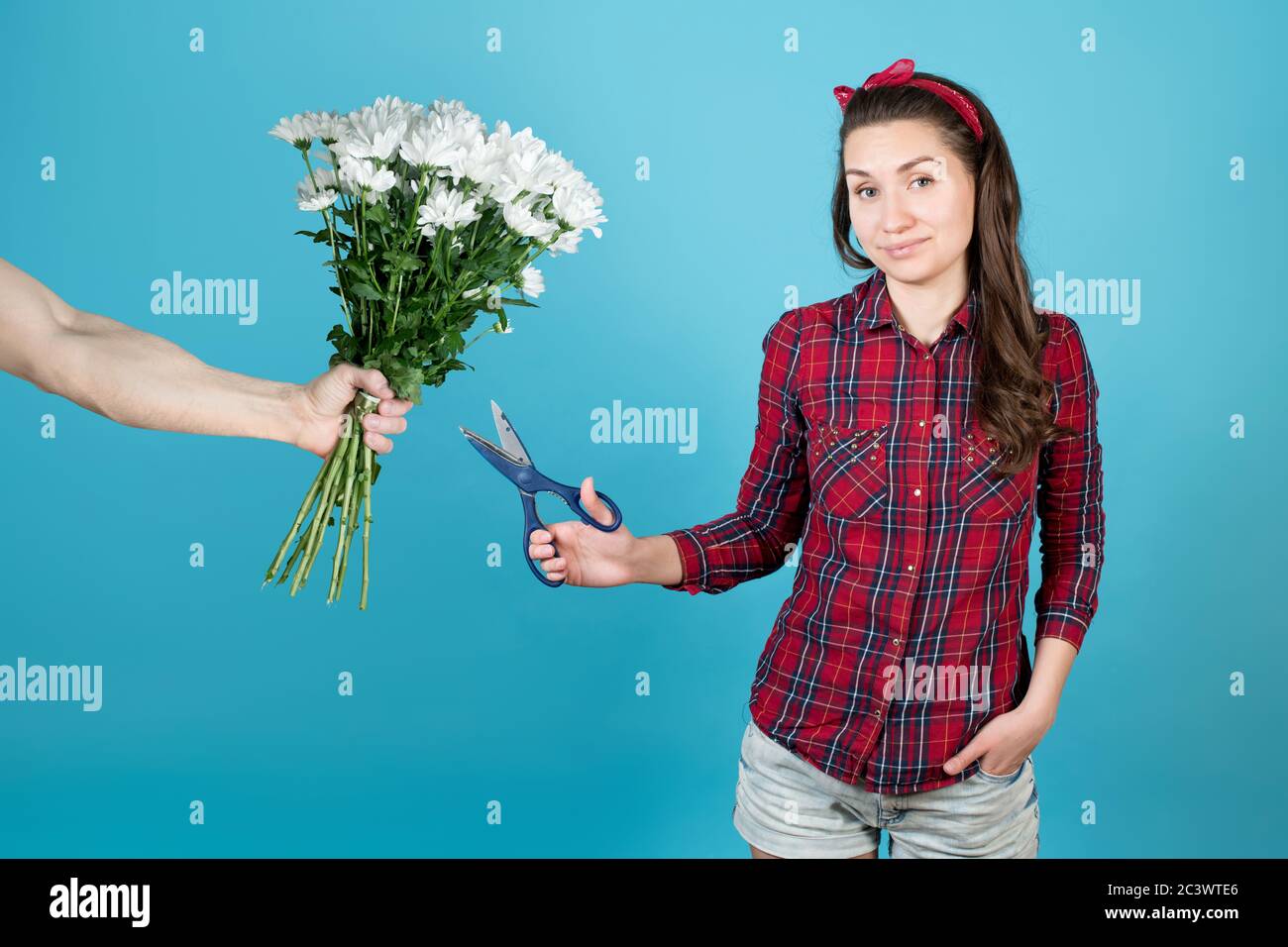 Der Mensch gibt einem Mädchen weiße Blumen, und sie beabsichtigt, sie verächtlich zu schneiden Stockfoto