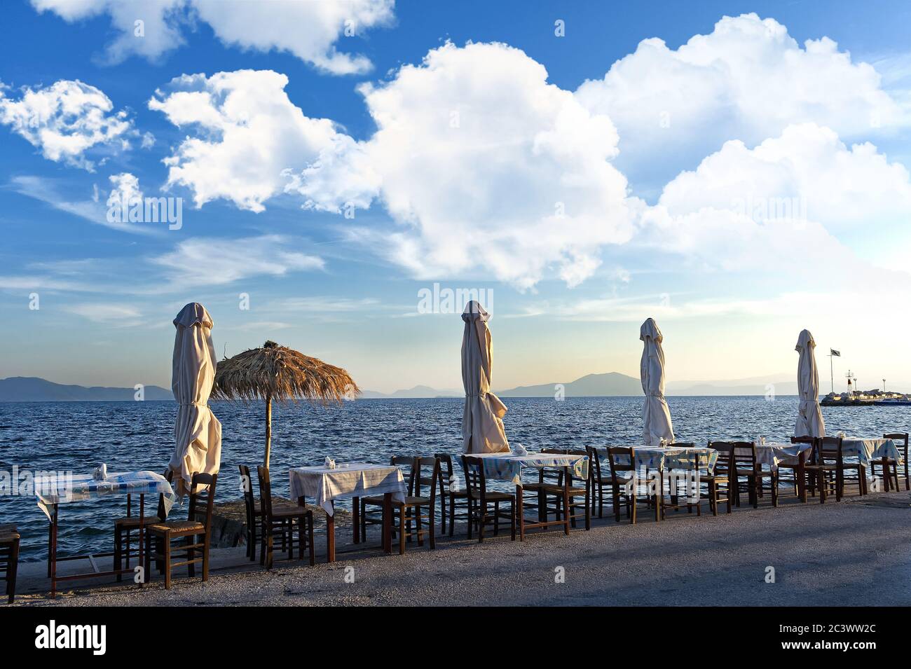 Mediterrane Meereslandschaft, griechische Tavernen Tische und Sonnenschirme Stockfoto