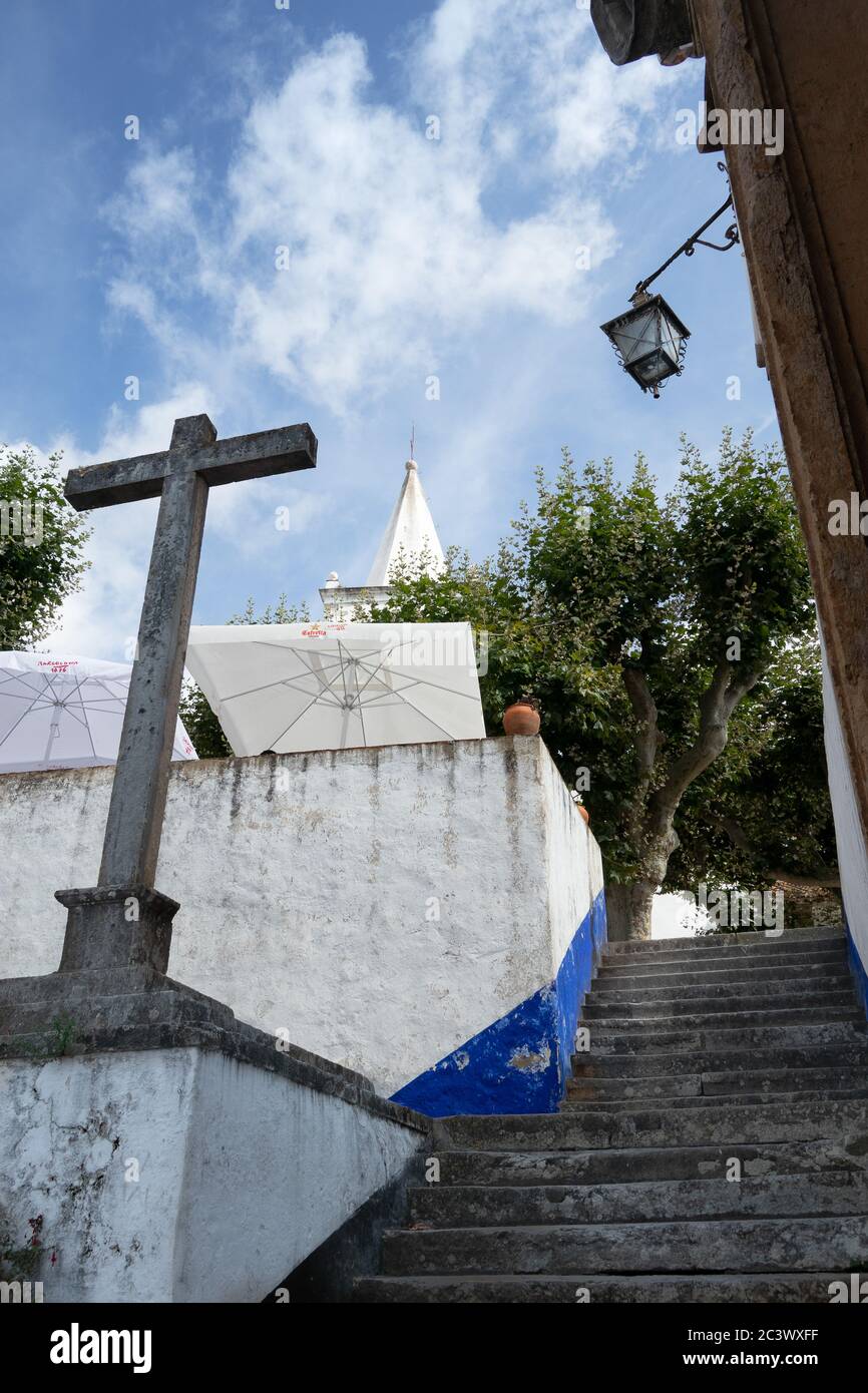 Blick auf alte Steinkreuz und gepflasterten engen Straße in Obidos Dorf Portugal Stockfoto