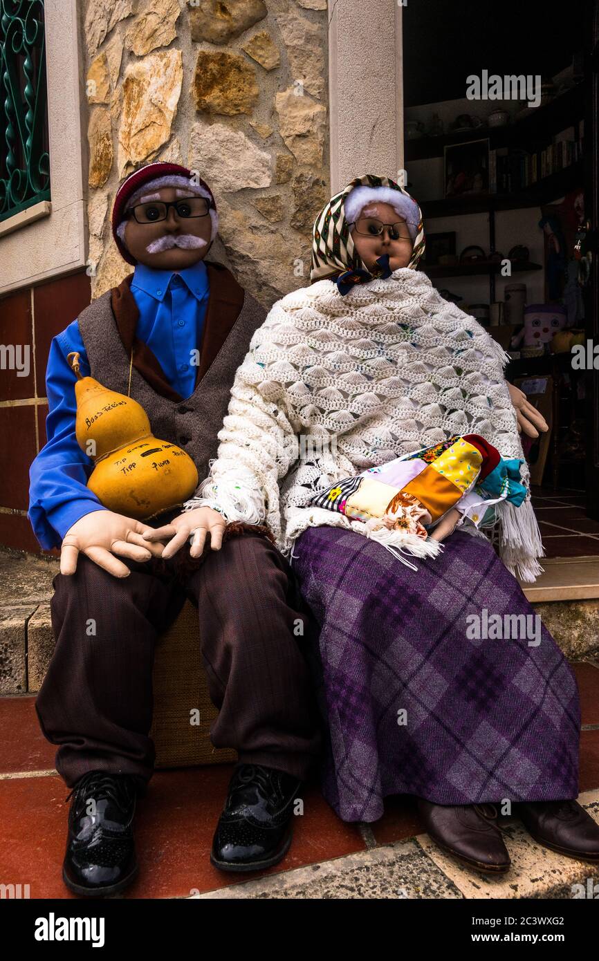 Zwei lustige Dummies Mann und Frau sitzen nebeneinander. Gut gekleidete alte traditionelle Kleidung mit einem Trinkgeld-Geldbehälter Stockfoto
