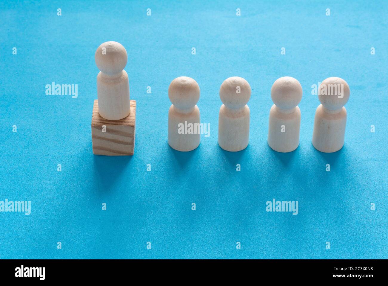 Hölzerne menschliche Figur auf dem Würfel. Erfolgreiche Führungskraft, Teamarbeit und Organisation. Chef und Untergebene. Individualität und Überlegenheit. Zielerreichung, Stockfoto