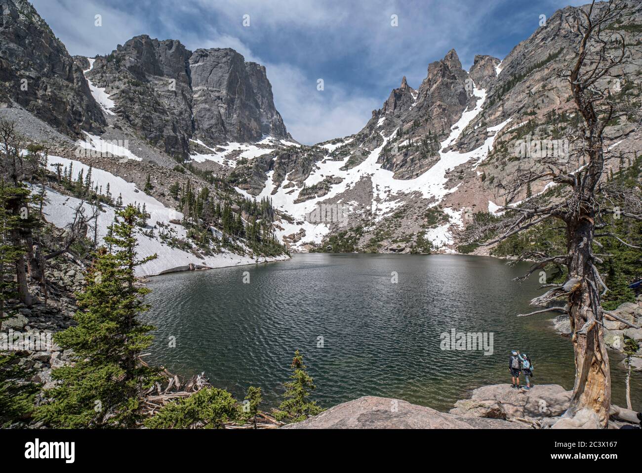 Emerald Lake im Rocky Mountain National Park von der Küste mit Blick auf den See, entfernte Berge, Wolken und Vordergrundfelsen Stockfoto