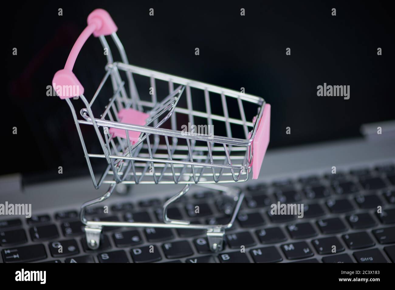 Pinkfarbener Mini-Warenkorb auf einer Laptop-Tastatur als Konzept für den Online-Einkauf Stockfoto