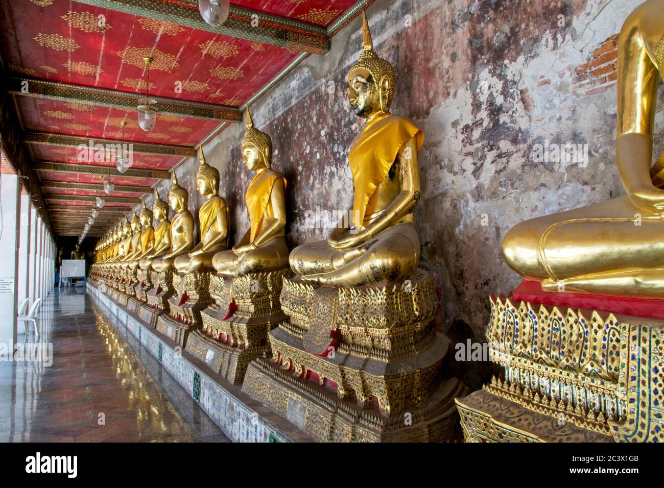 Wat Suthat Tempel, Gebäude und Meditation Bhudda Statuen. Reihe von sitzenden vergoldeten Buddha-Ikonen unter dem Deckel, die von vorne nach hinten zurücktreten Stockfoto
