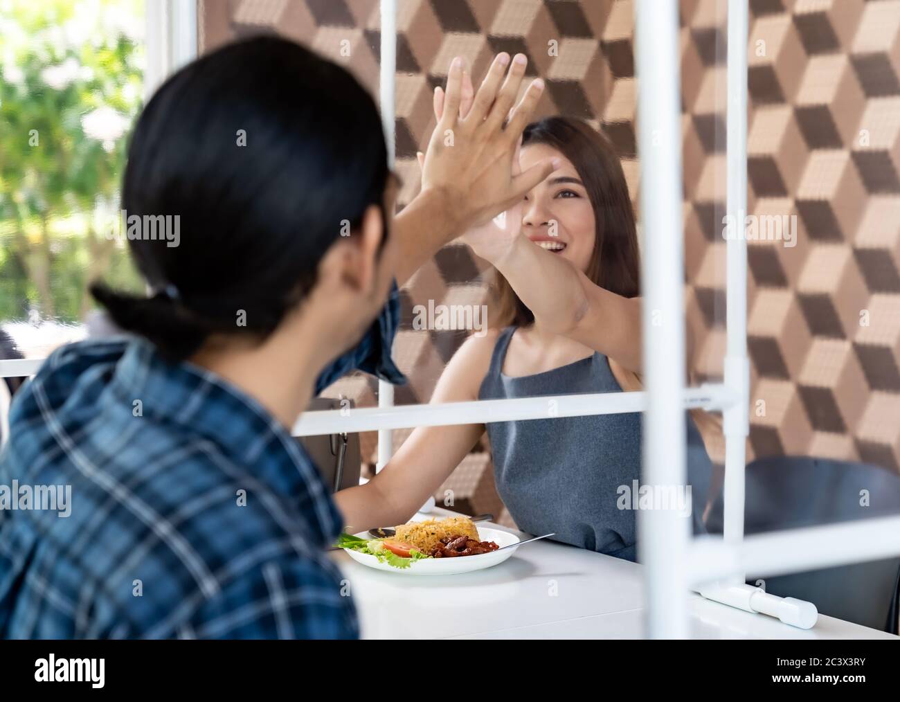 Asiatische junge Paar essen zusammen in neuen normalen sozialen Abstand Restaurant mit Tisch bespießt Trennwand reduzieren Infektion von Coronavirus covid-19 p Stockfoto