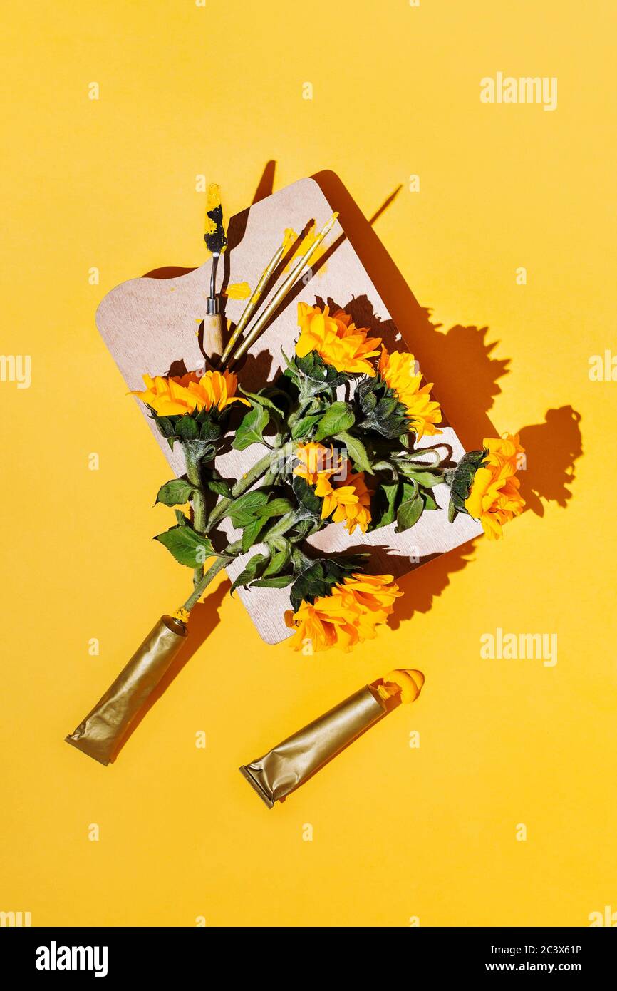 Kreative Flatlay mit Künstlerbedarf und Sonnenblumen auf Gelb Stockfoto